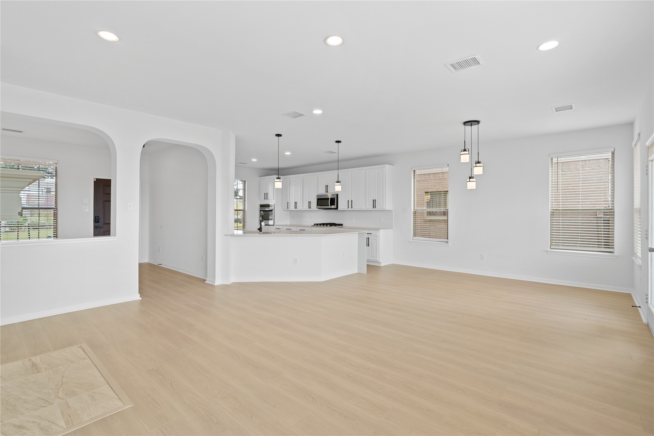 Living Area & Kitchen Wide-angle view showcases the spacious main living area flowing directly into the kitchen, accented by arched architectural openings, modern lighting, and plentiful natural light. Living Area & Kitchen Wide-angle view showcases the spacious main living area flowing directly into the kitchen, accented by arched architectural openings, modern lighting, and plentiful natural light.