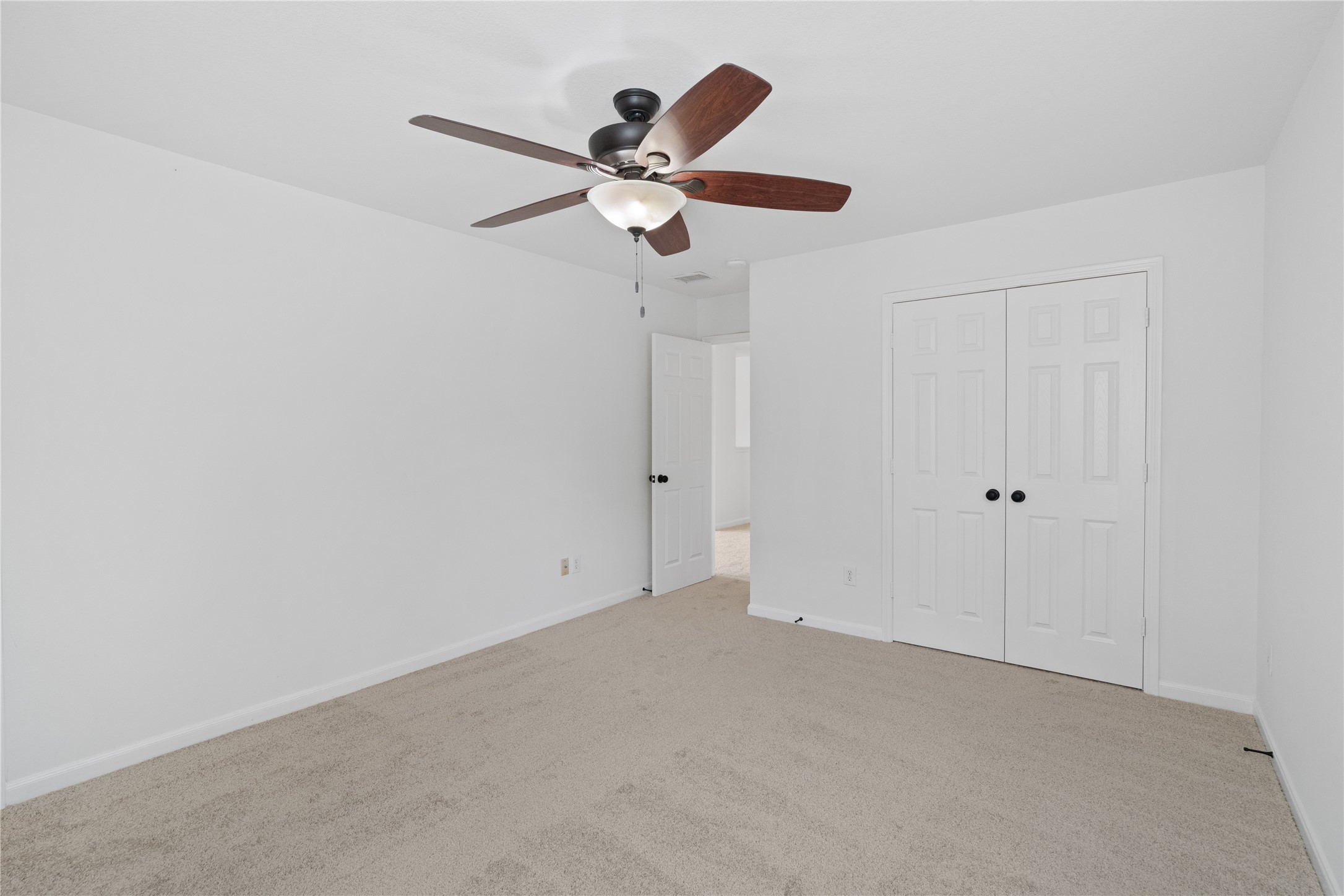 Bedroom  Reverse view highlights the double-door closet, ceiling fan, and versatile wall space for a variety of furniture arrangements.