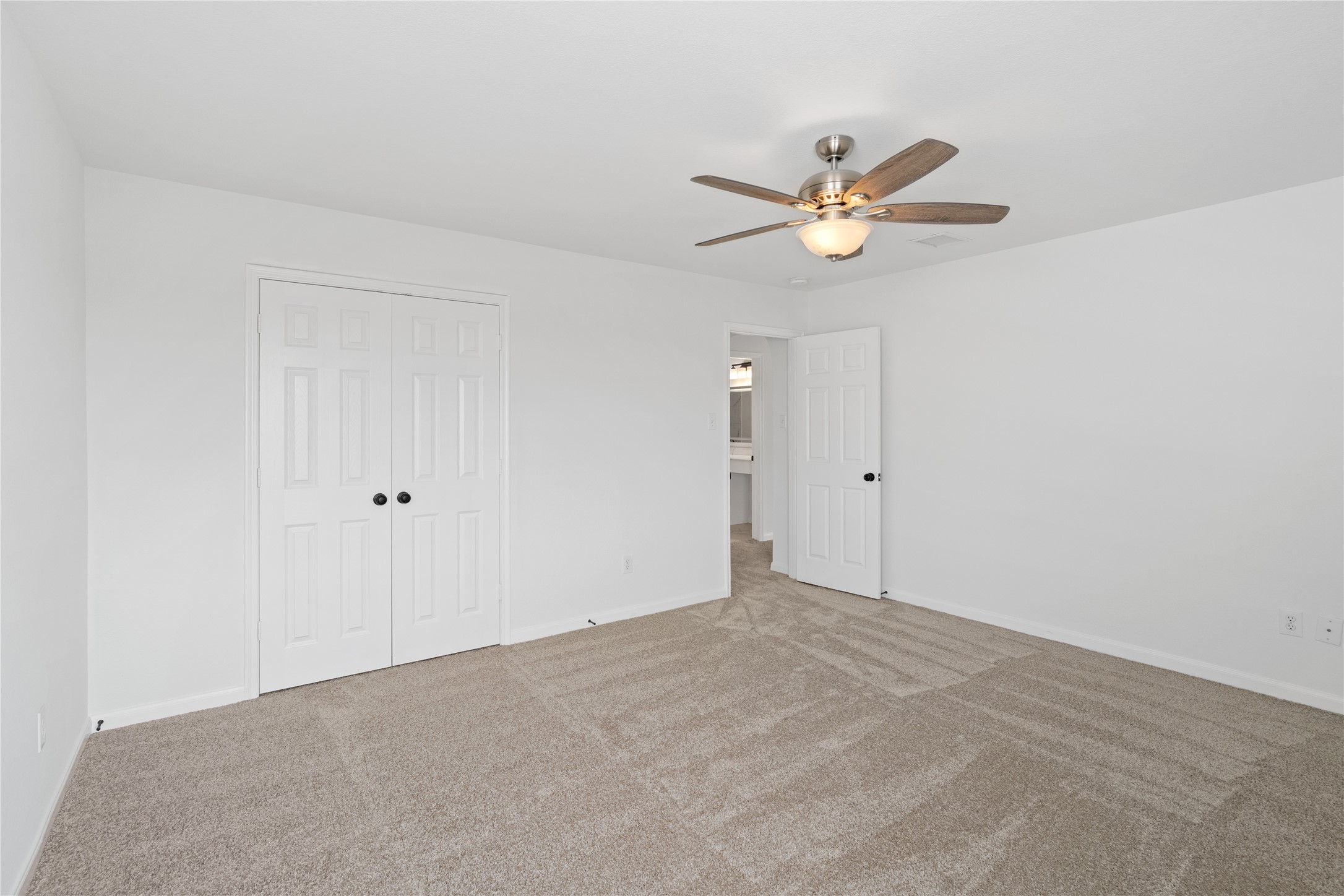 Bedroom  Alternate view highlights the generous proportions, double-door closet, neutral carpeting, and ceiling fan with integrated lighting.