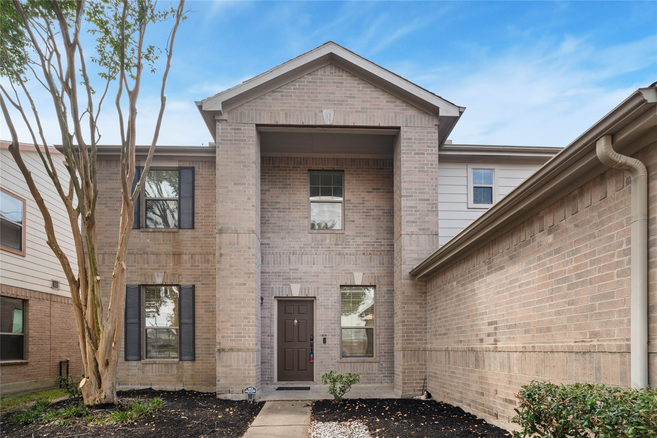 Front Entry  Closer view of the two-story brick faade showcases the recessed covered entrance, architectural brick detailing, and landscaped walkway.