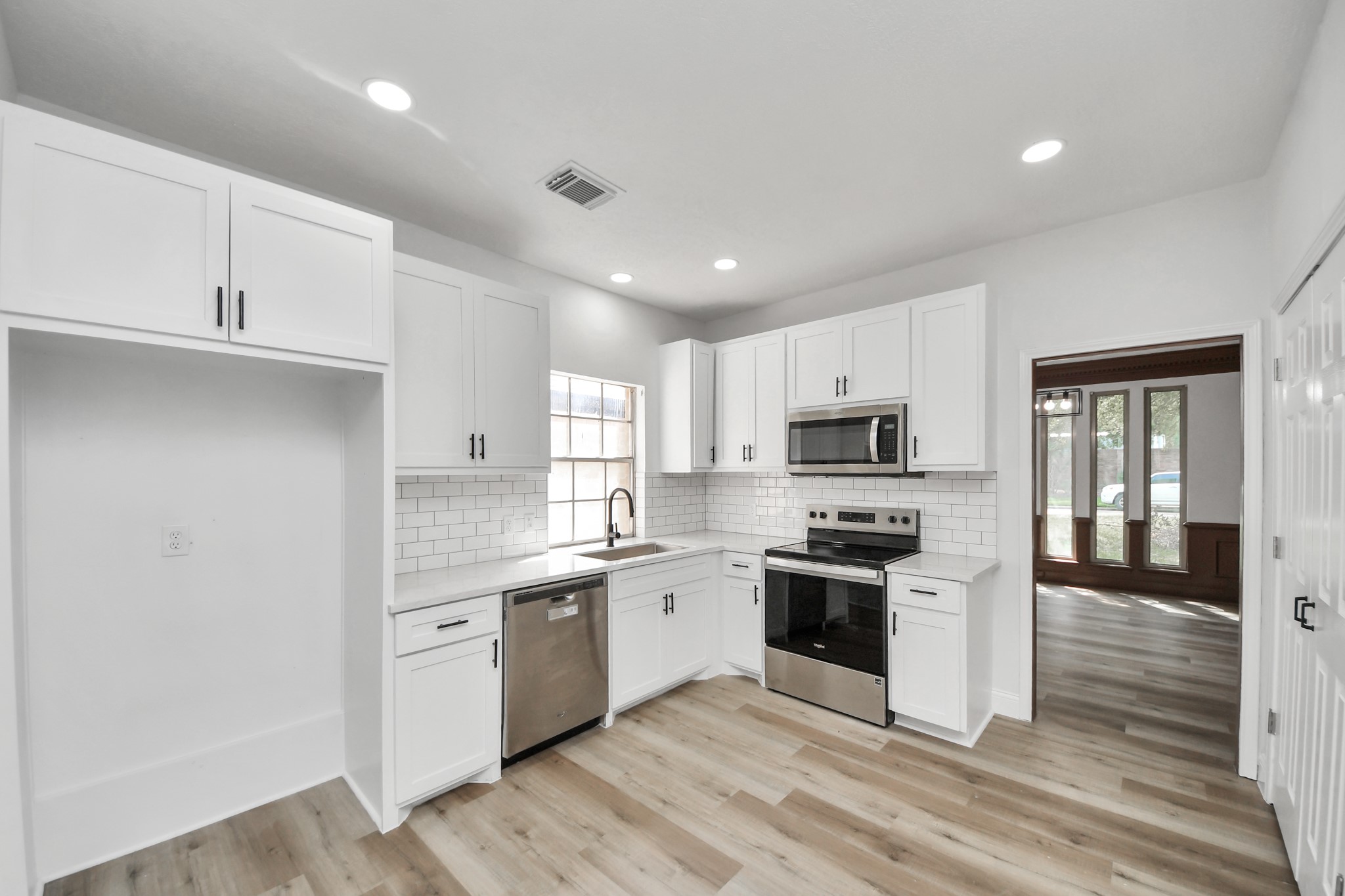 Modern kitchen with sleek white cabinetry, stainless steel appliances, and stylish subway tile backsplash, offering ample natural light and a spacious layout.