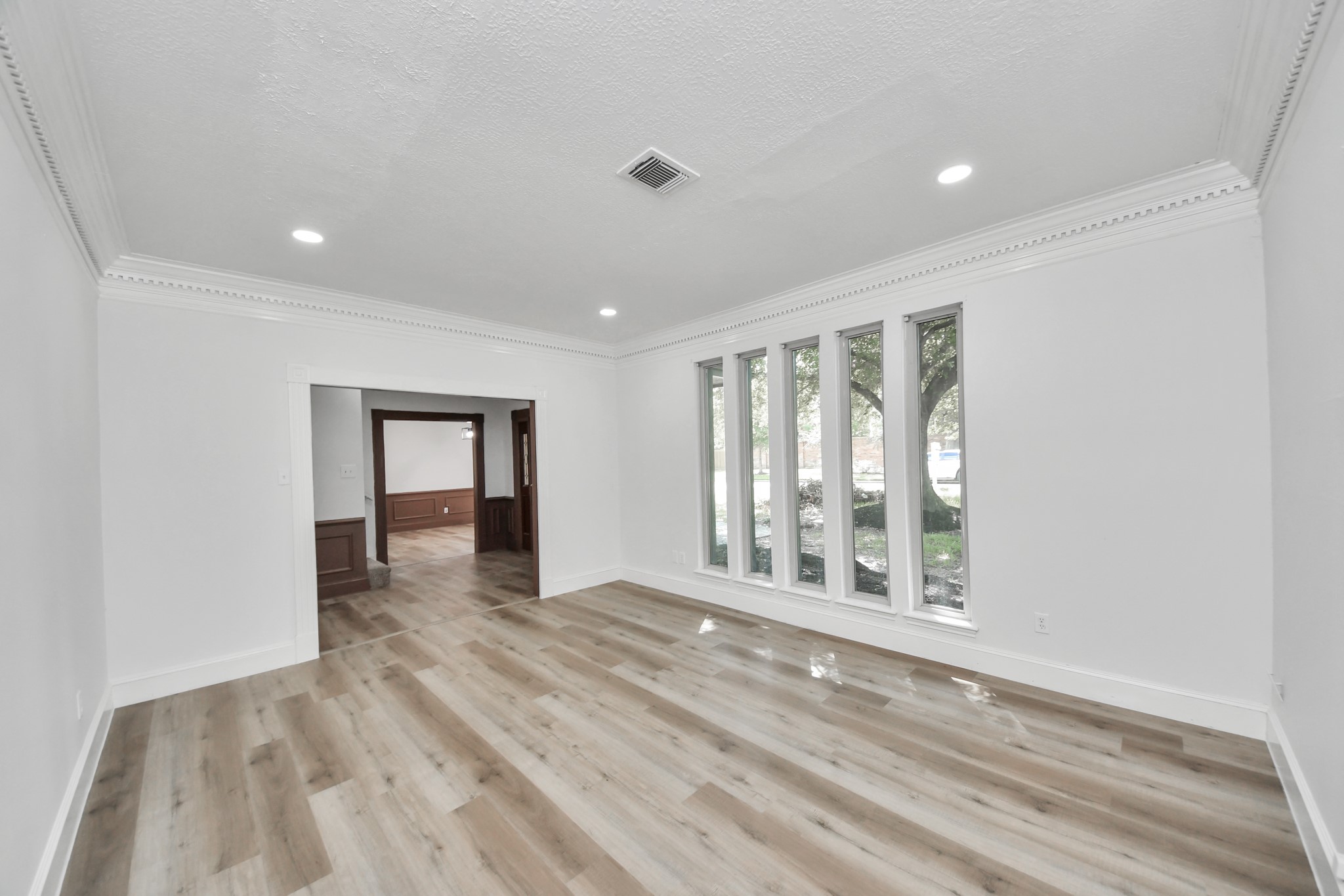 Bright and spacious living area featuring elegant crown molding, sleek recessed lighting.