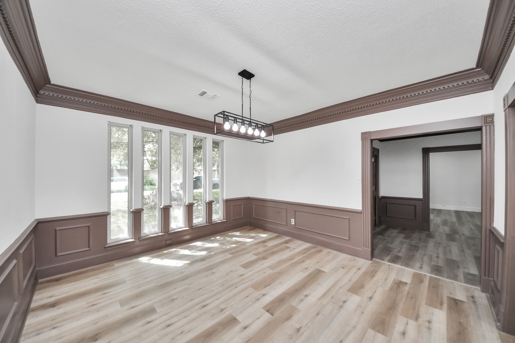 Bright dining area with large windows, elegant wainscoting, and modern light fixture, offering a warm and inviting space for gatherings.