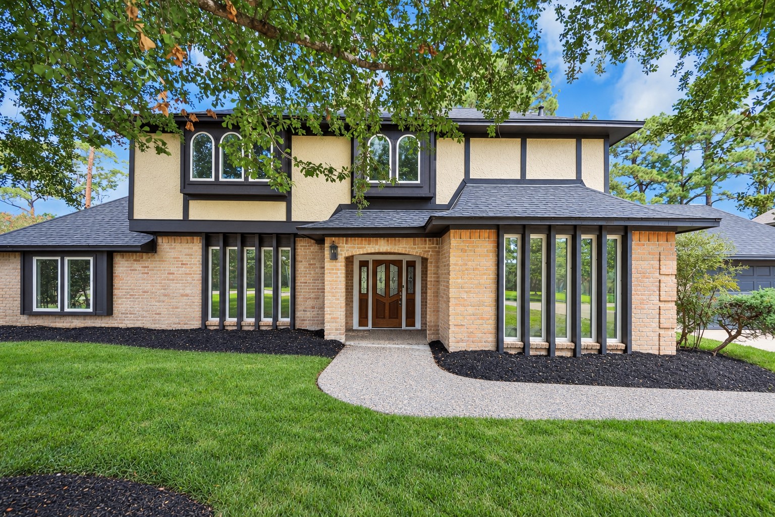 Charming two-story home , featuring large windows and a welcoming entryway.