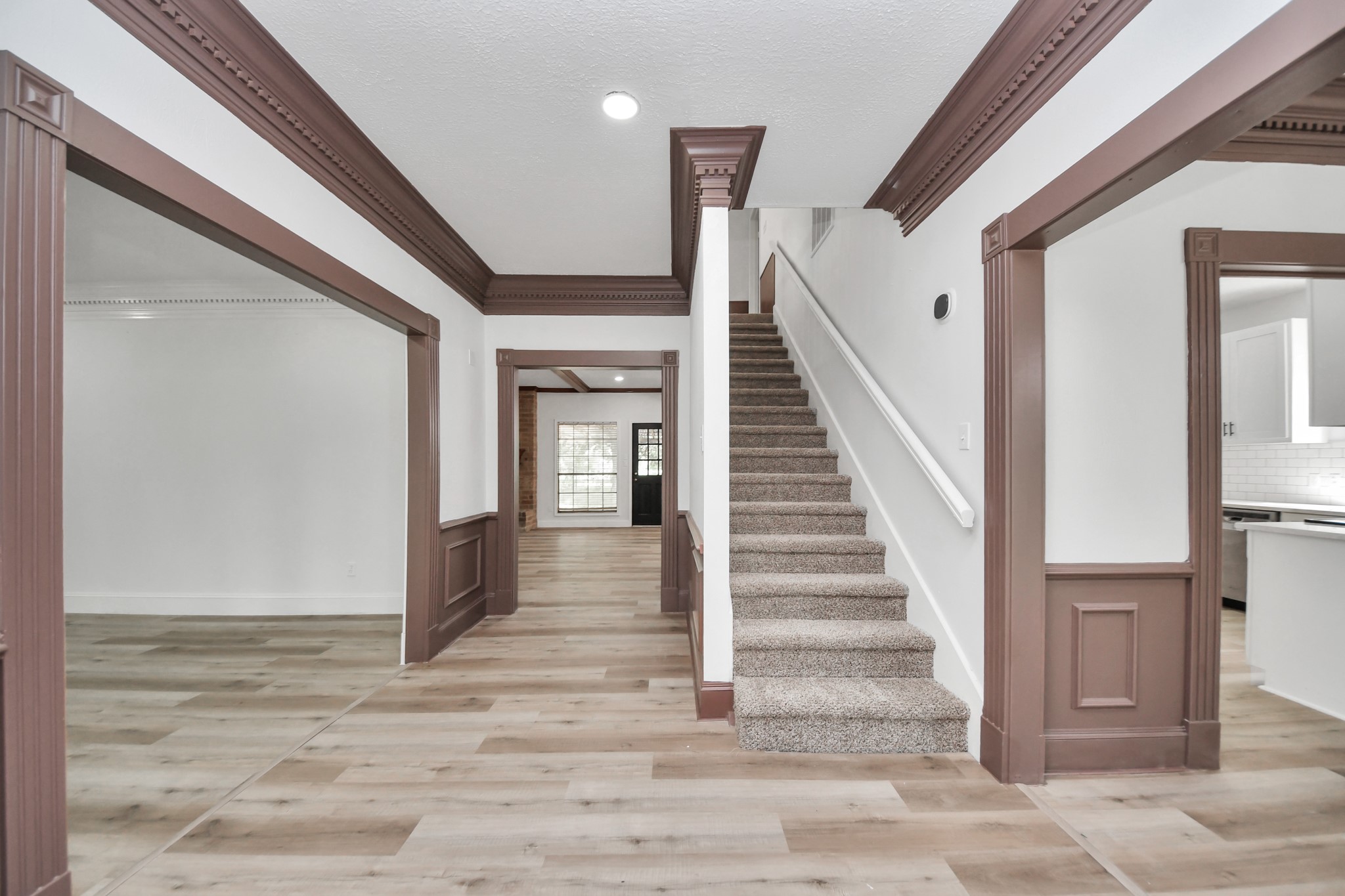 Charming entryway with elegant wood trim, modern flooring, and a welcoming staircase leading to the upper level.