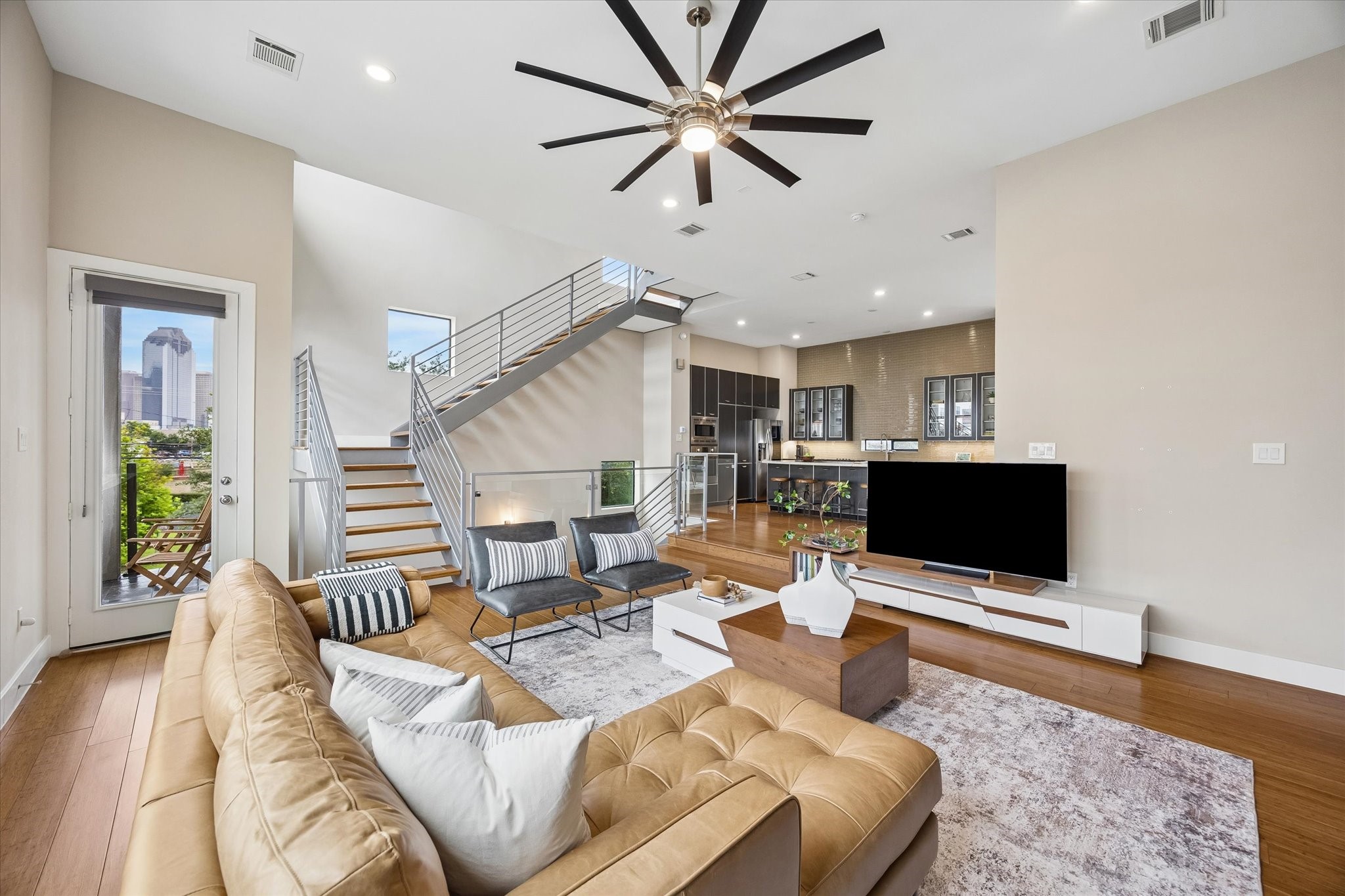 Soaring ceilings and wide windows make this living room feel open, bright, and full of energy. The modern staircase, sleek fireplace, and easy access to the outdoor balcony add to the polished feel of this impressive main living level.