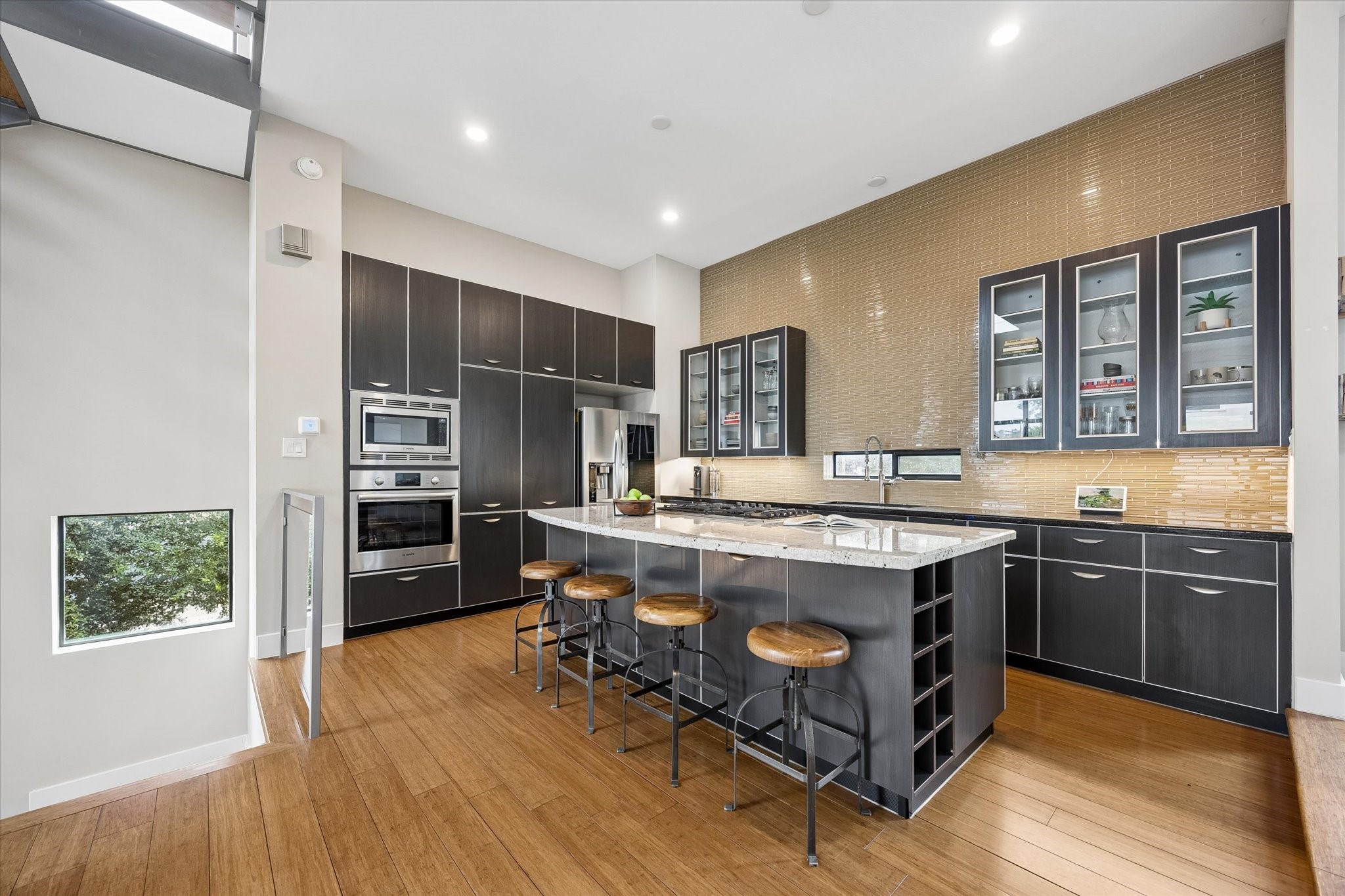 The main living level is designed for connection, with the kitchen, dining, and living areas all flowing together in one bright, welcoming space. The dramatic stacked stone fireplace, warm wood flooring, and sleek modern details give the home a fresh, elevated feel from every angle.