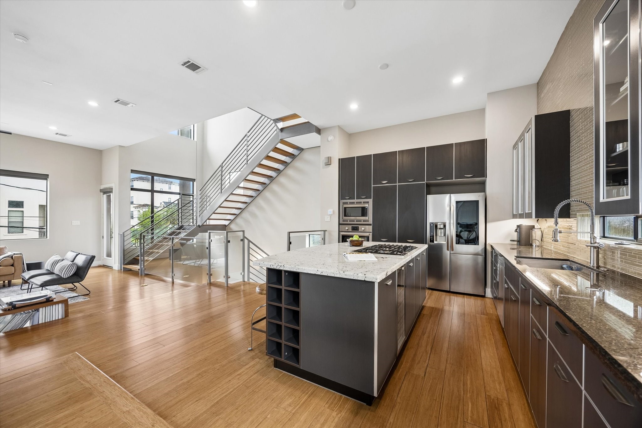 The island kitchen has all the ingredients you need to entertain in style, with sleek modern cabinetry, granite countertops, a statement tiled wall, high-end stainless-steel appliances, and a layout that keeps the home chef connected to all the action.