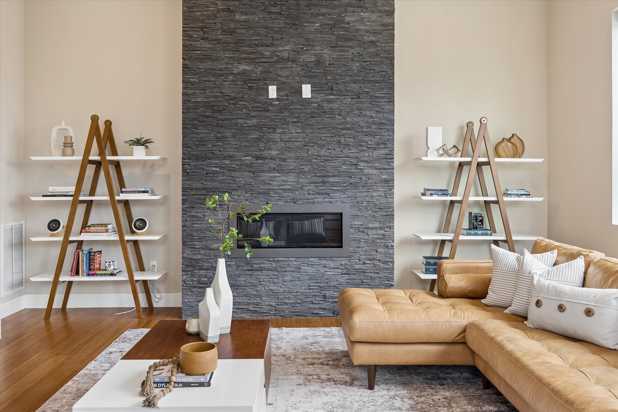The sleek fireplace creates a striking focal point with its dramatic stacked stone surround, built-in backlighting, and clean contemporary design. The bold texture and modern lines give the living room a polished feel while keeping the overall look fresh and inviting.