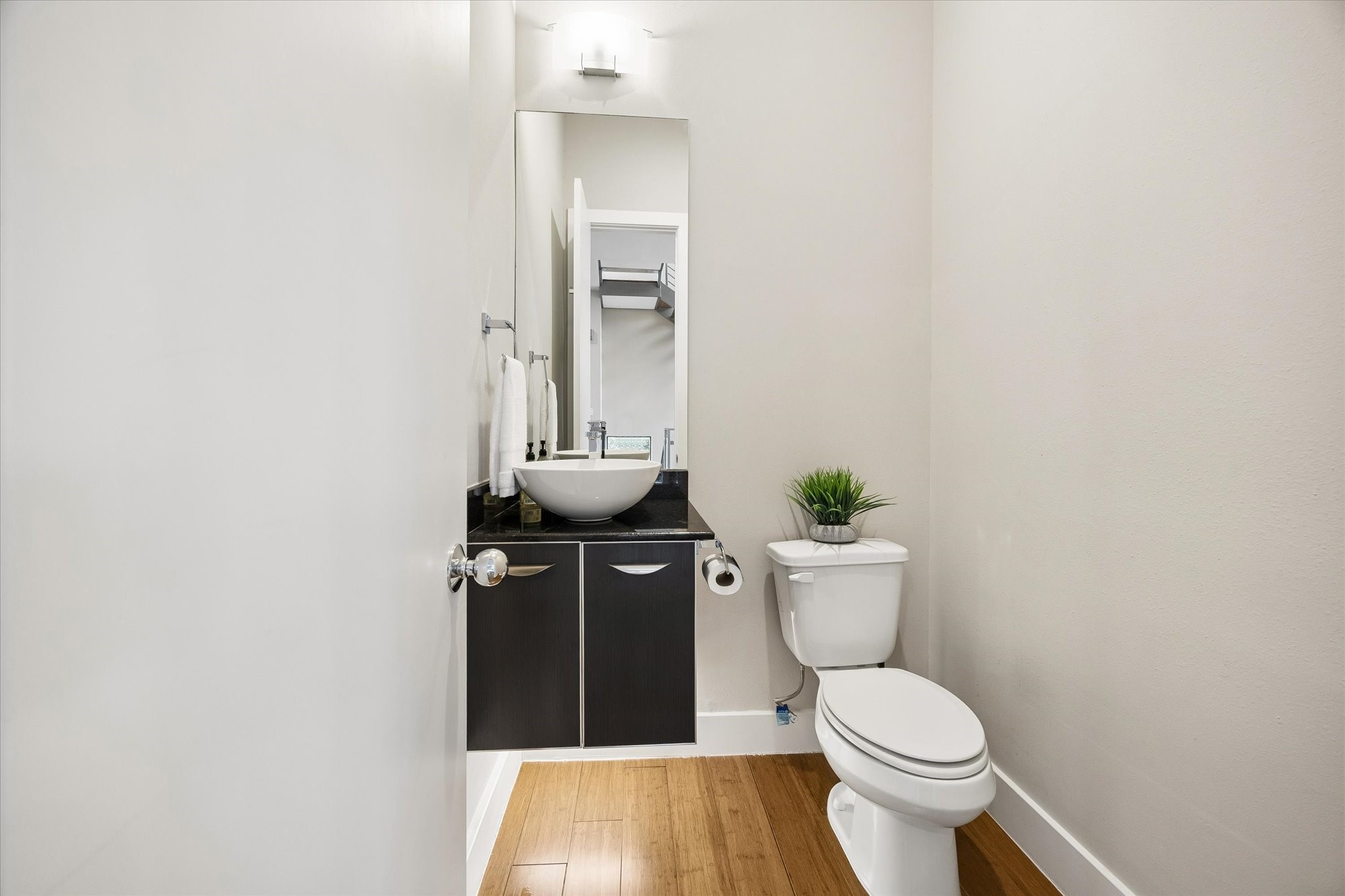 The main floor powder bath is convenient for daily use and guests, with a clean modern look that fits right in with the rest of the home. A floating vanity, vessel sink, and under-cabinet lighting add a stylish touch to this practical everyday space.