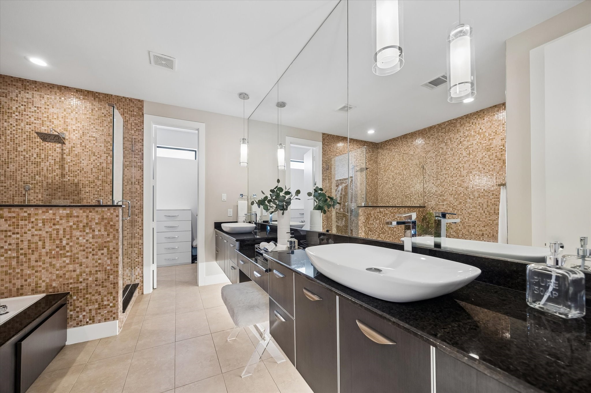 Enjoy a daily dose of luxury in this spa-like ensuite, where the floating vanity pairs dual vessel sinks with sleek granite countertops, under-mount lighting, and a wall-to-wall mirror for a bright, polished feel. It is a beautiful space to start the morning, wind down at night, and make everyday routines feel like something special.