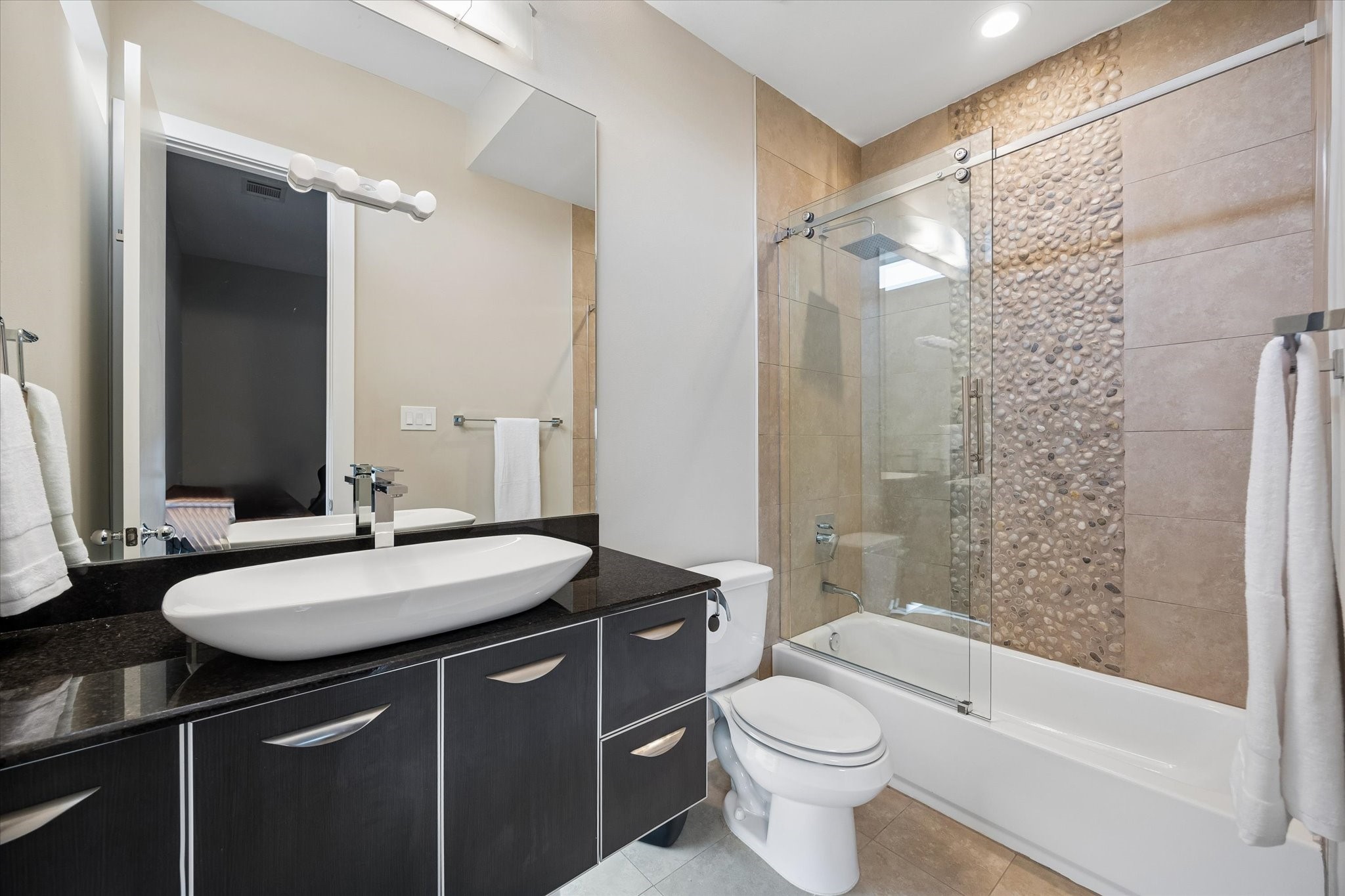 Guests will love having their own private ensuite bath, complete with a sleek vessel sink, plenty of storage, and a beautifully tiled tub and shower combo. It's a stylish, comfortable setup that makes the third-floor suite feel even more private and inviting.