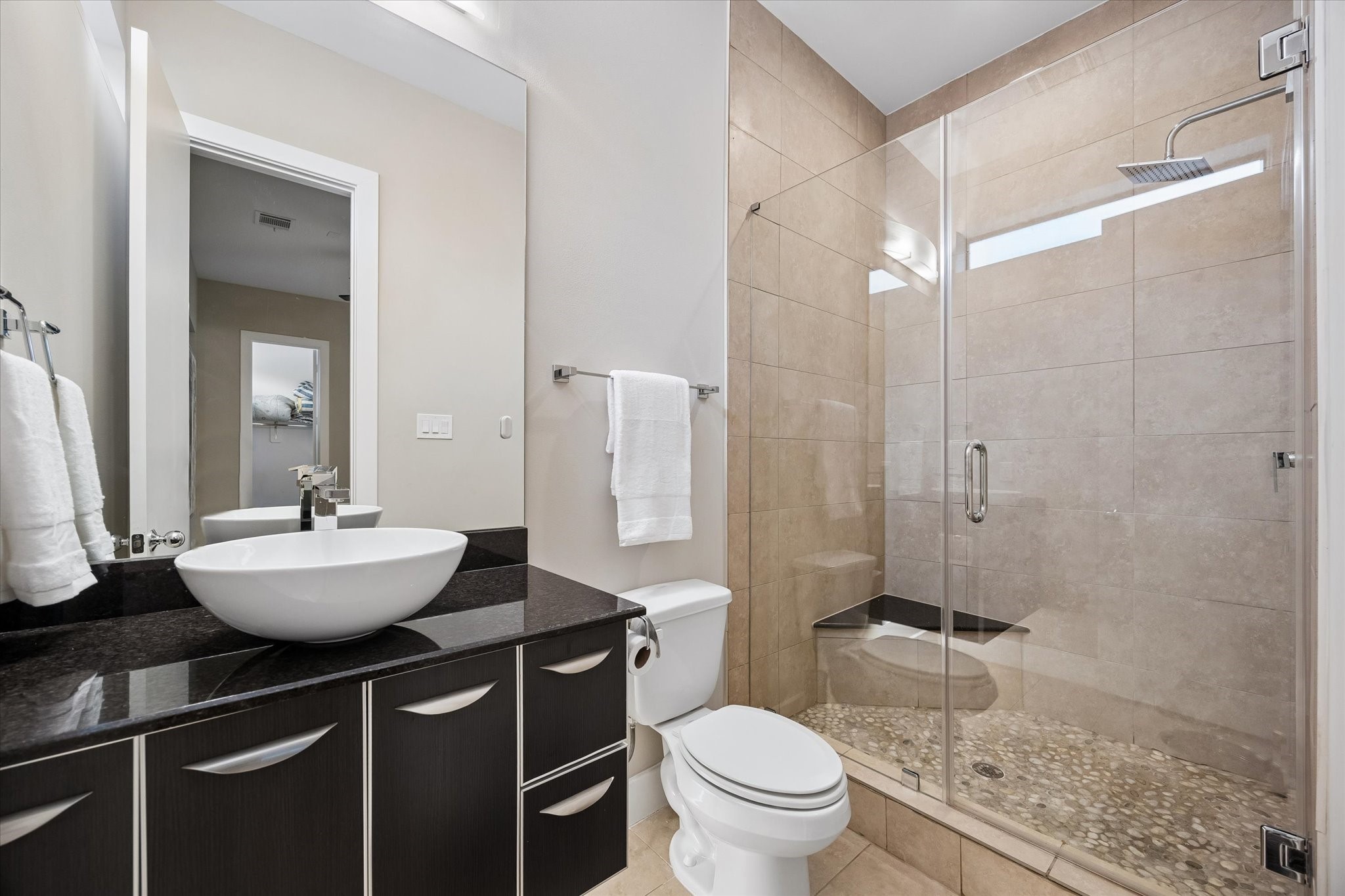 The ensuite bath adds comfort and privacy to the first-floor suite with a sleek vanity, vessel sink, and a spacious glass-enclosed shower. This thoughtful setup makes the ground floor feel like its own private retreat while keeping the floor plan flexible for real life.