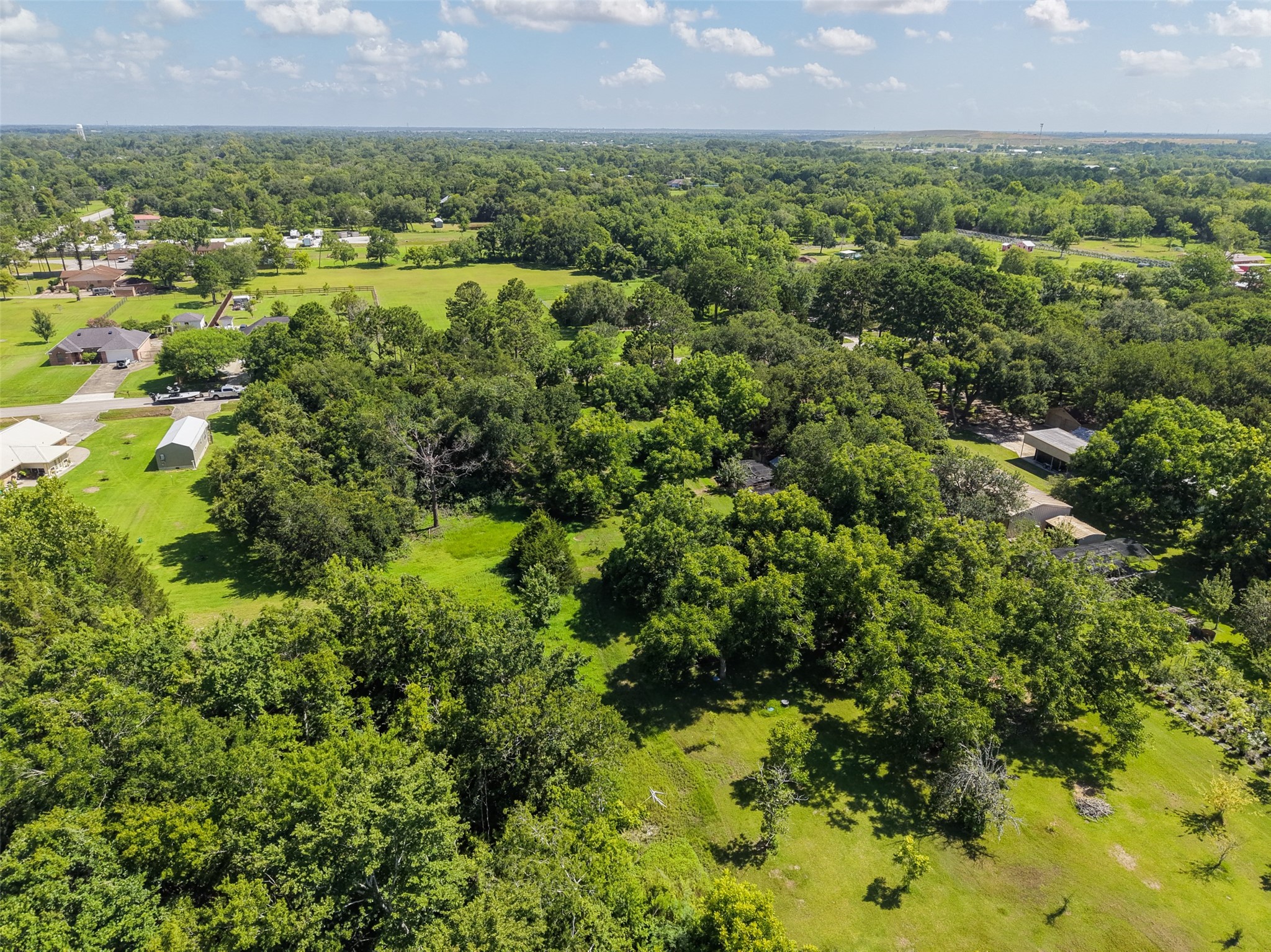 This aerial perspective reveals additional open areas within and around the property's mature tree canopy. With nearly 68,000 sq. ft. of land, buyers have room to think beyond the house itselfperhaps incorporating generous outdoor living, gardens, recreational areas, a workshop or other improvements into the overall site plan. The property's size allows those elements to coexist without sacrificing the privacy created by the surrounding trees.