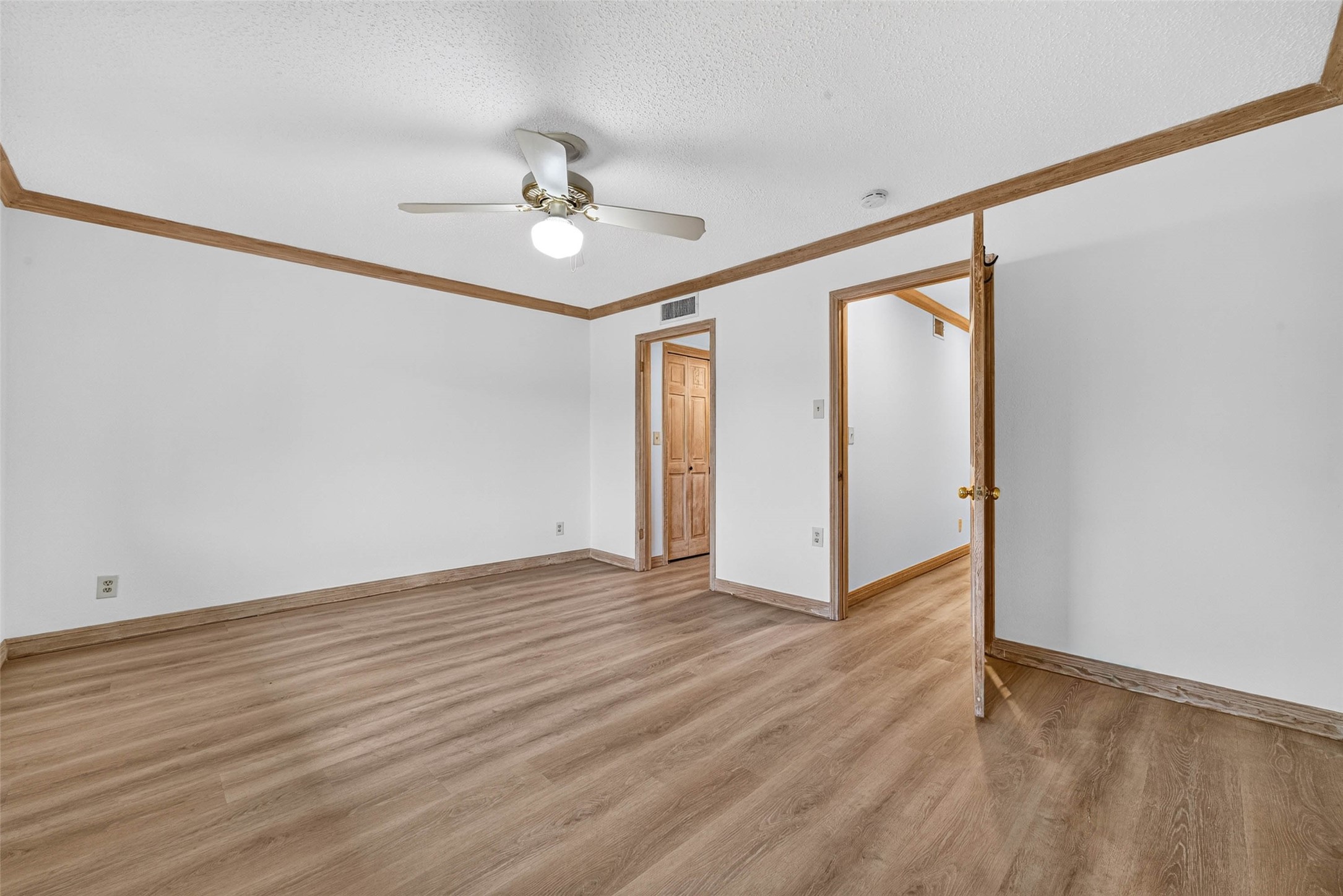 Spacious room featuring elegant flooring, bright white walls, and a ceiling fan for comfort.
