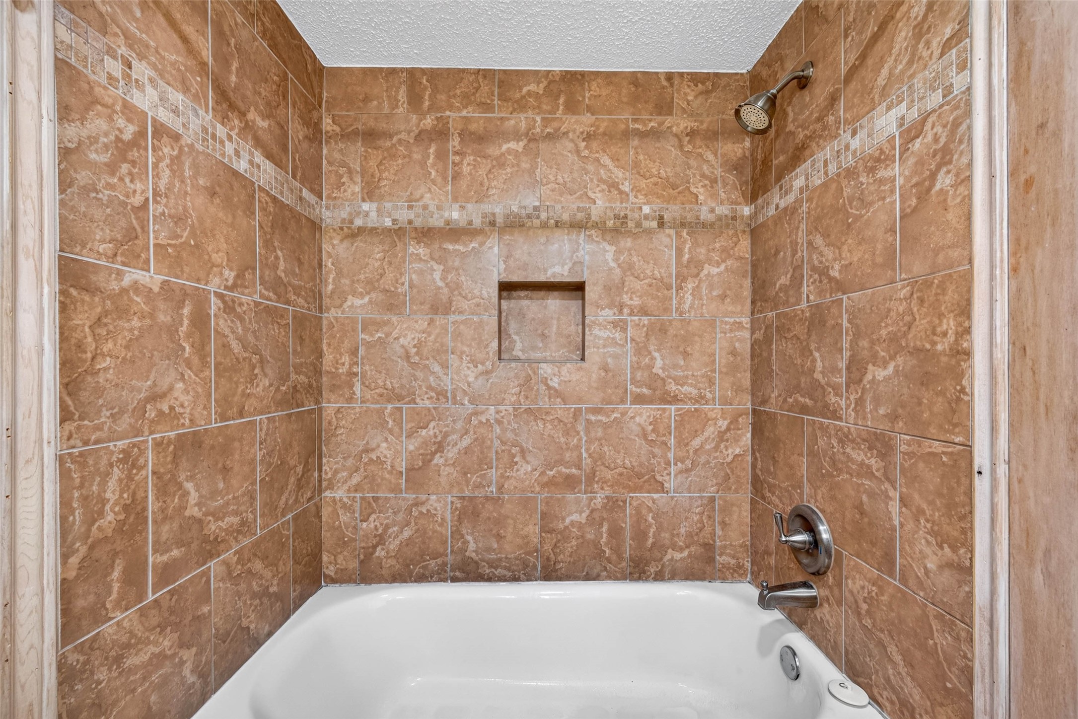 Elegant bathroom featuring a bathtub with stylish brown tile surround