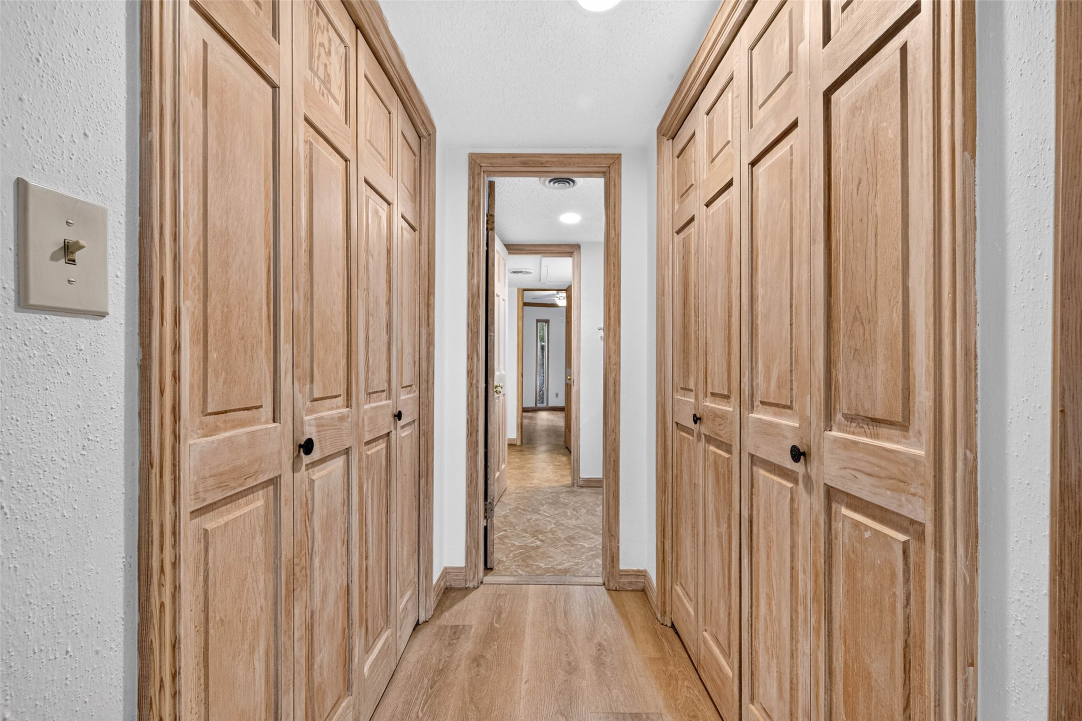 A charming hallway features ample storage with beautifully crafted wooden closet doors on both sides