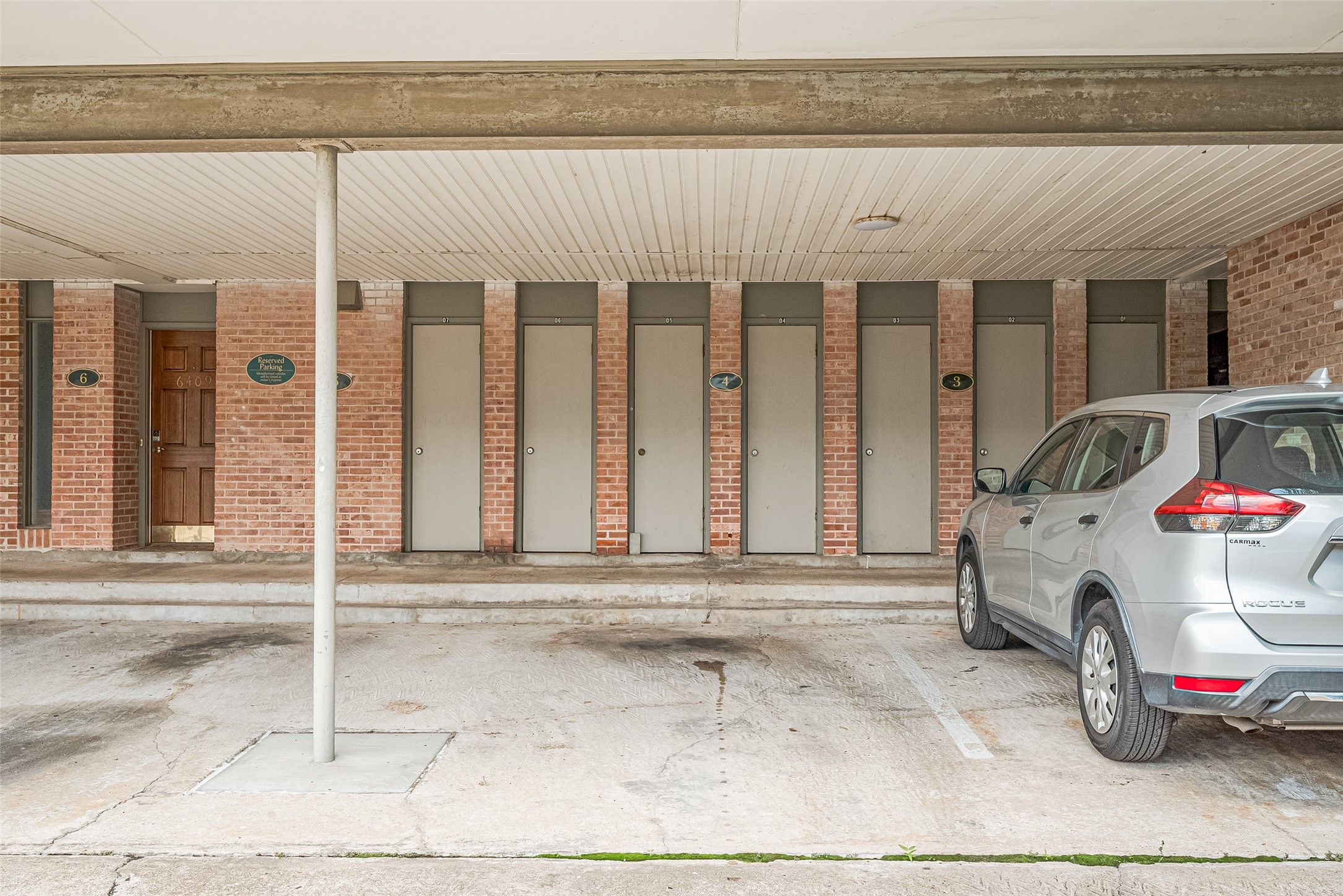 Covered parking area with secure storage units and brick exterior, providing convenience and functionality.