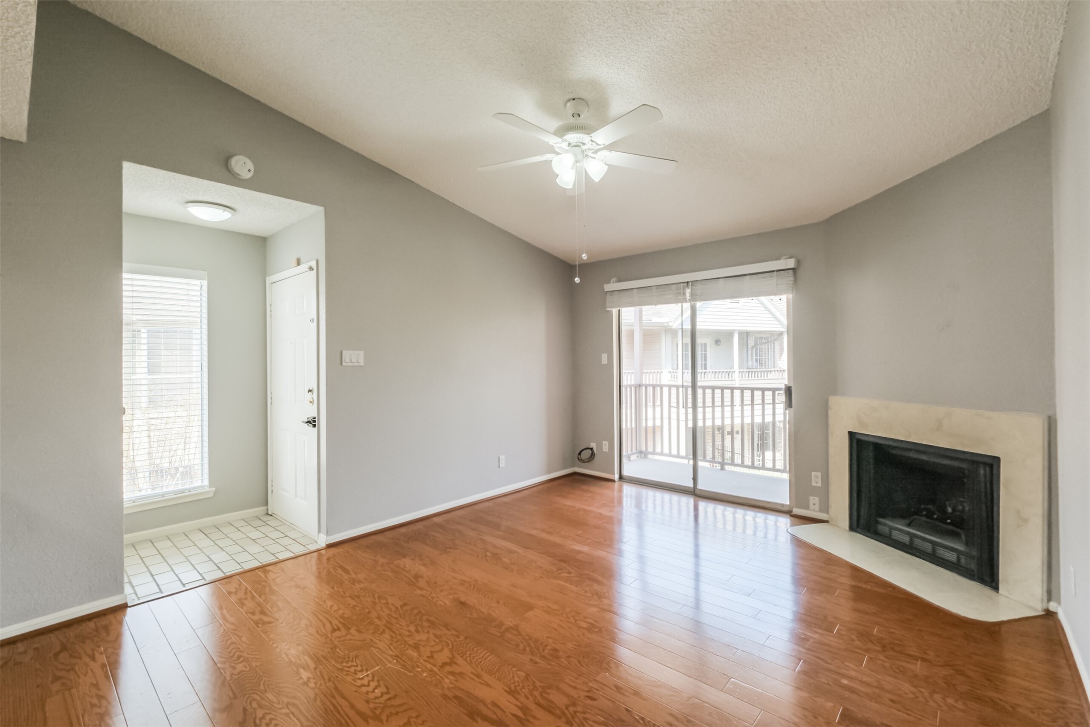 Inviting living room filled with natural light from large windows, complemented by hardwood floors and a cozy fireplace!
