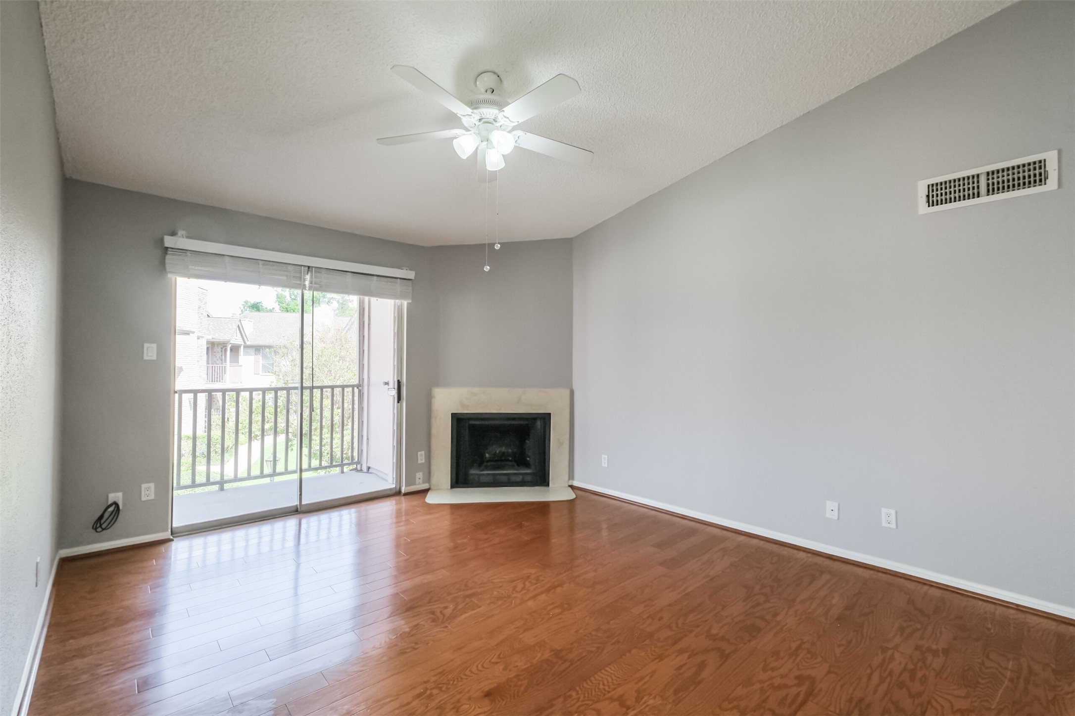 Inviting living room filled with natural light from large windows, complemented by hardwood floors and a cozy fireplace!