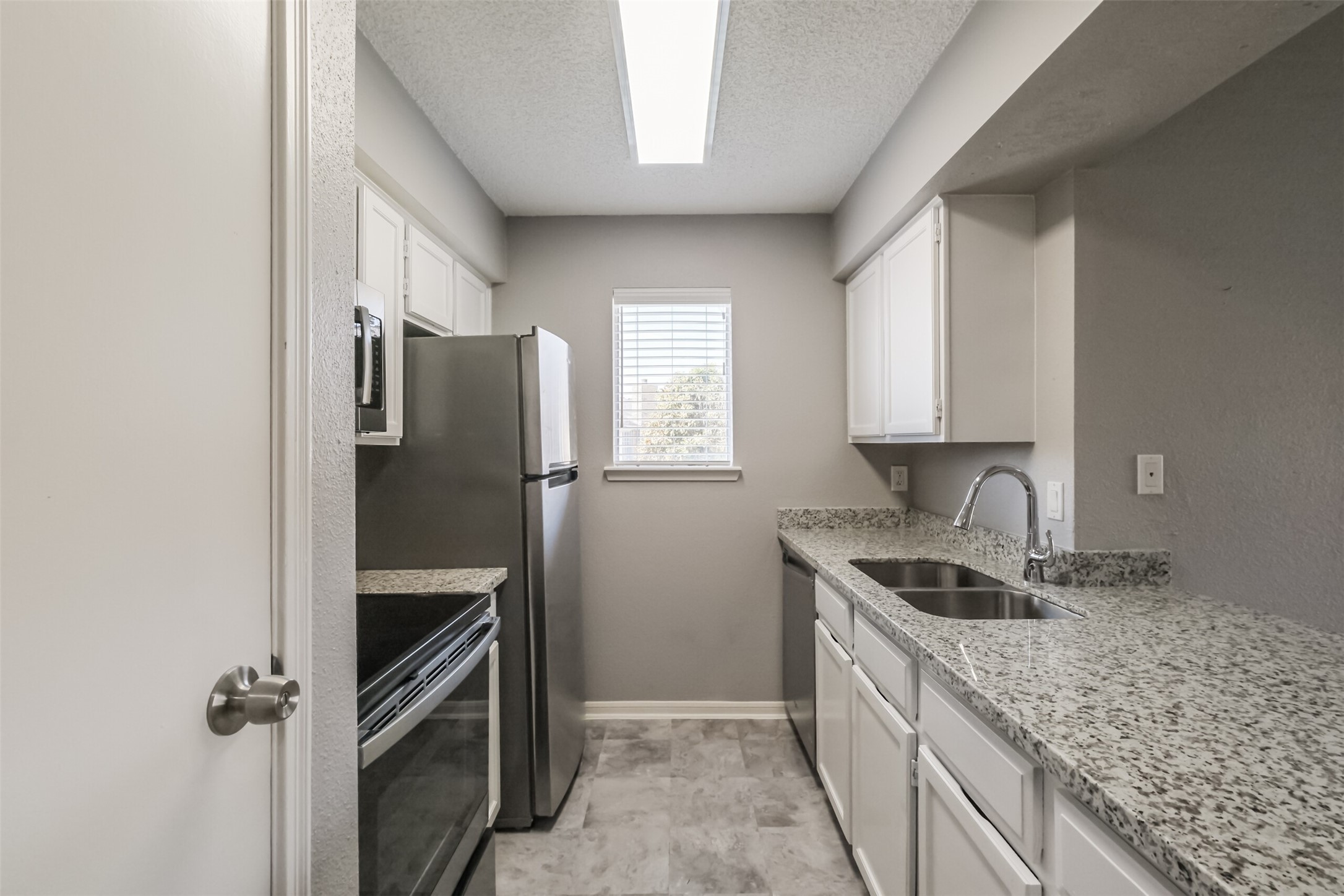 Updated kitchen featuring granite countertops, stainless steel appliances including a refrigerator, and plenty of cabinet storage!
