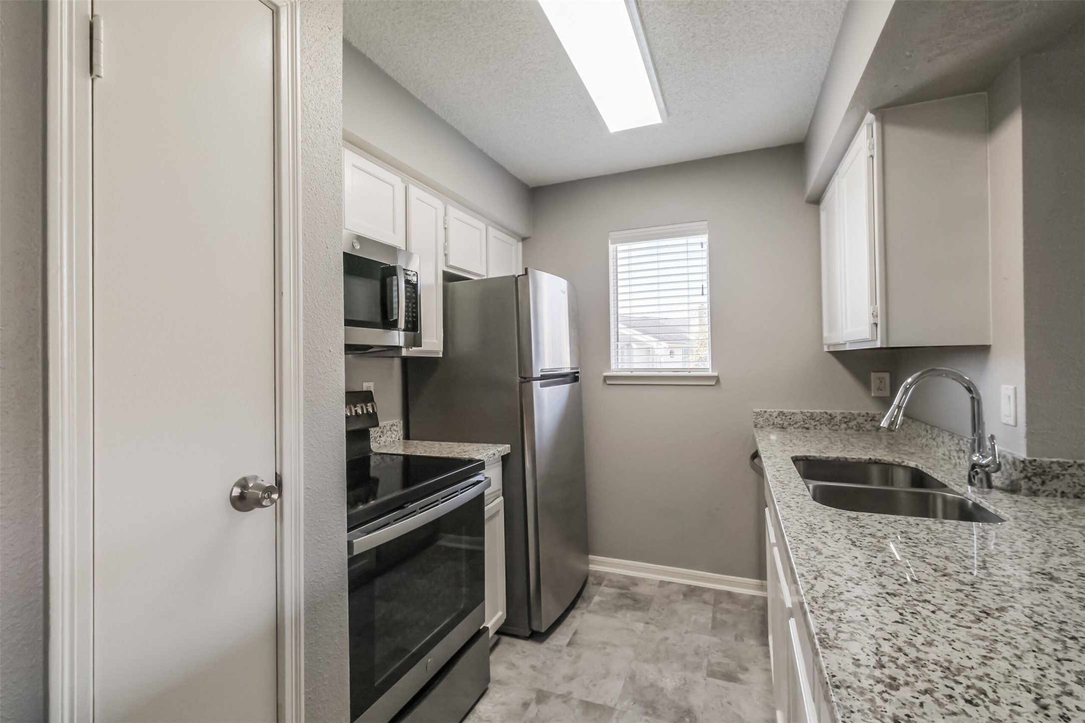 Updated kitchen featuring granite countertops, stainless steel appliances including a refrigerator, and plenty of cabinet storage!