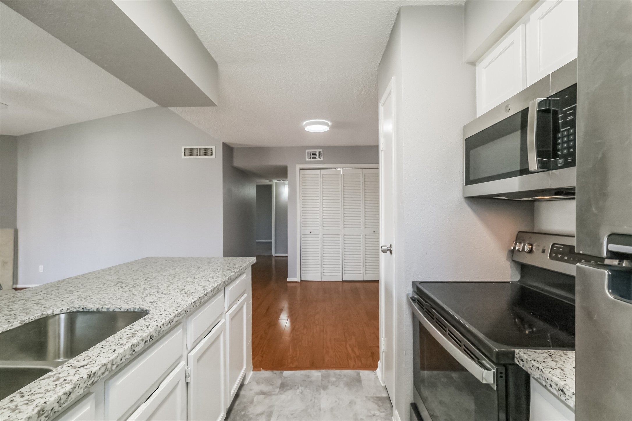 Updated kitchen featuring granite countertops, stainless steel appliances including a refrigerator, and plenty of cabinet storage!