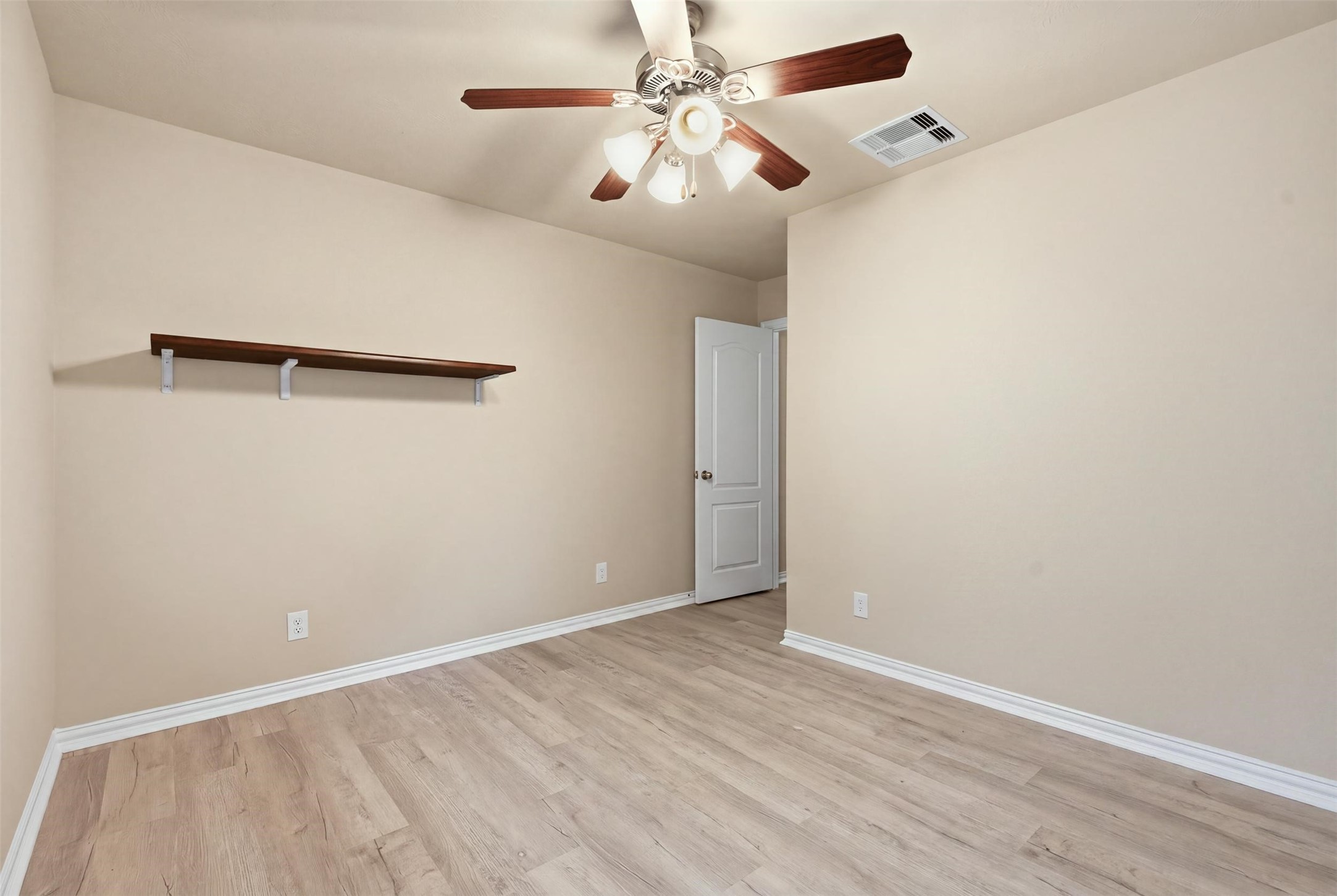 Clean, neutral and move-in ready, this bedroom includes a ceiling fan, a wall shelf and easy-care plank flooring.