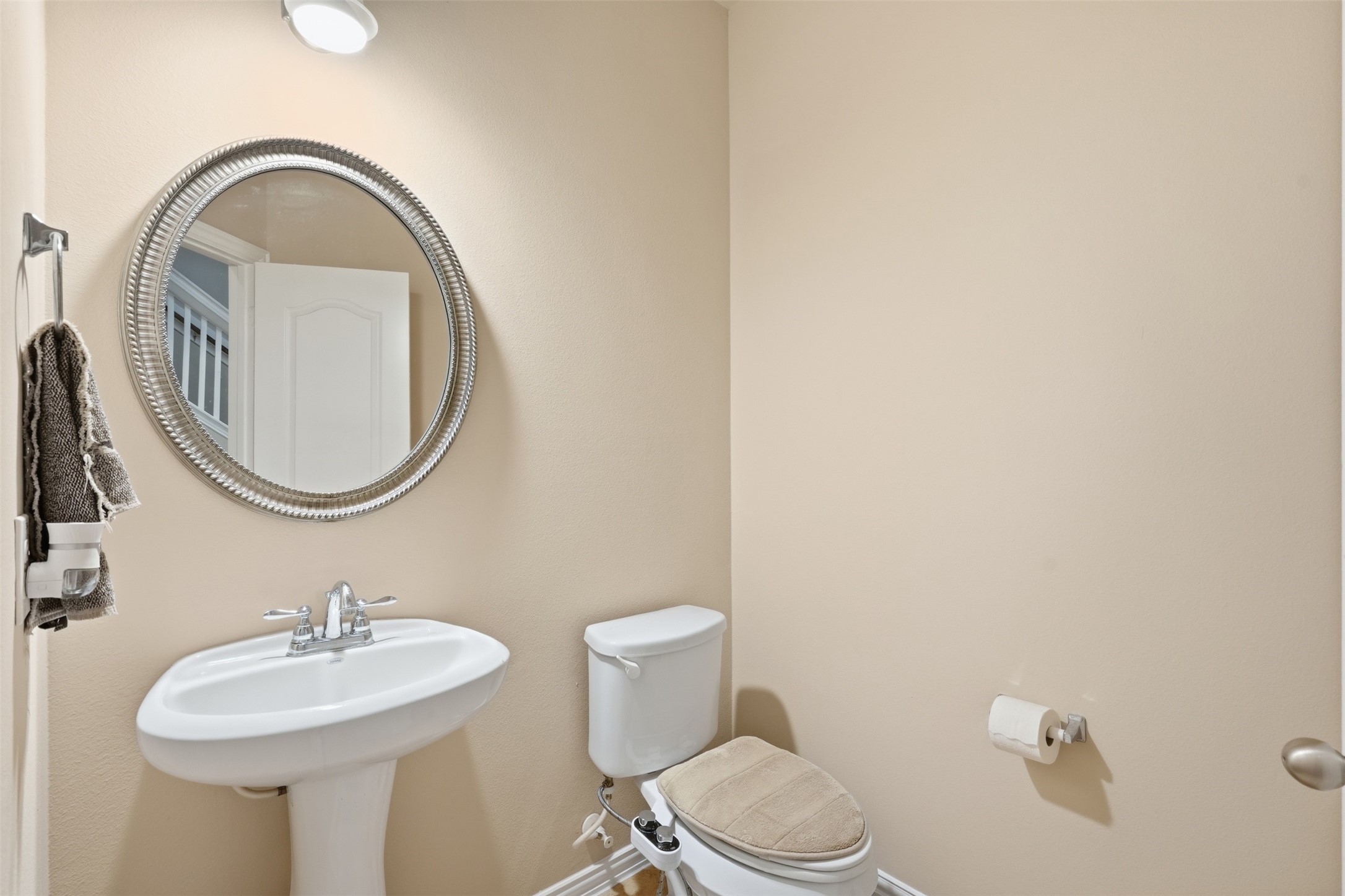 Guest-ready half bath on the main floor, with a pedestal sink and warm neutral walls.