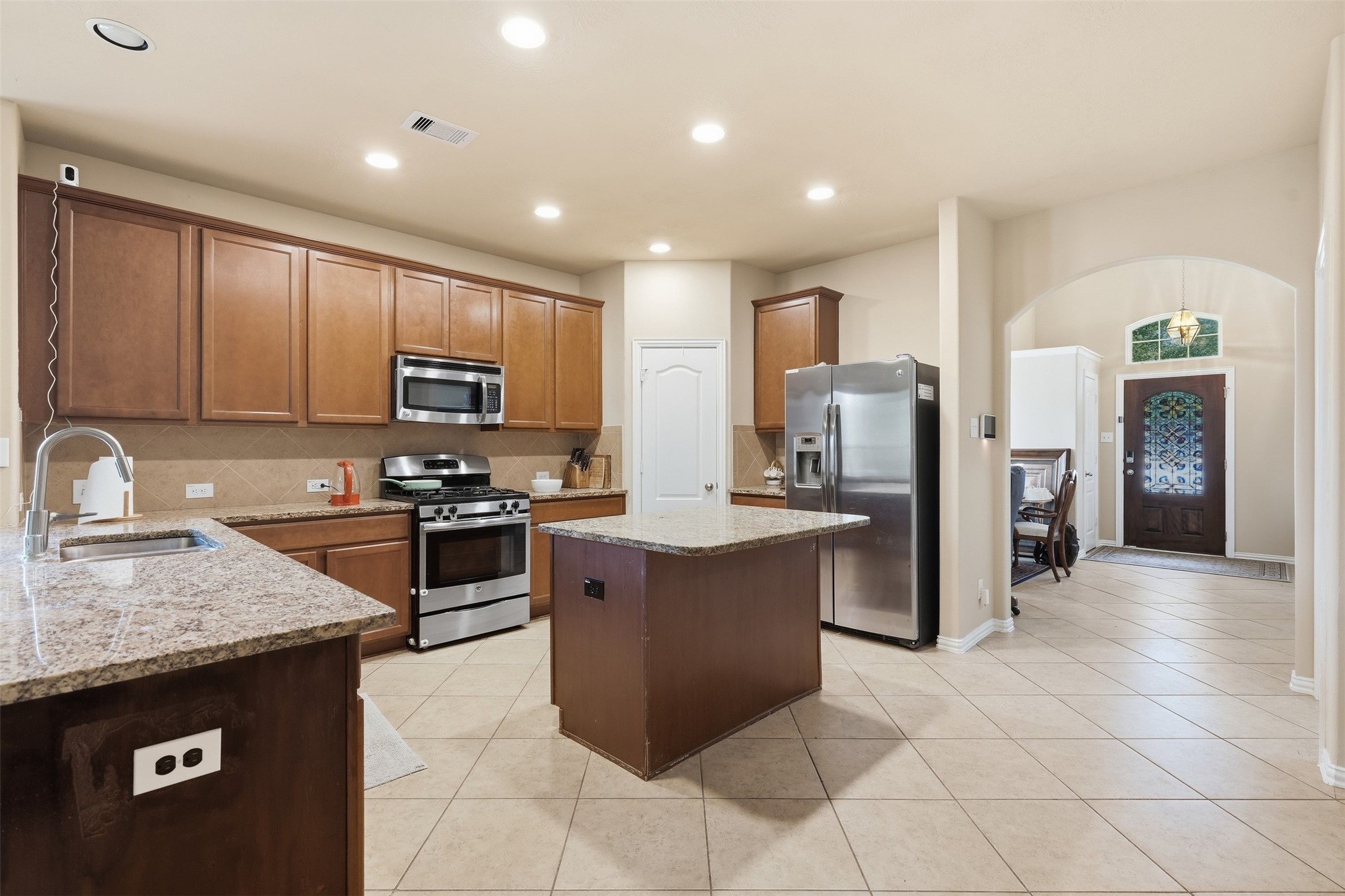 The kitchen everyone ends up in. Granite counters, a center island, gas range, stainless appliances, tile backsplash and recessed lighting, open to the dining area and entry. The kitchen everyone ends up in. Granite counters, a center island, gas range, stainless appliances, tile backsplash and recessed lighting, open to the dining area and entry.