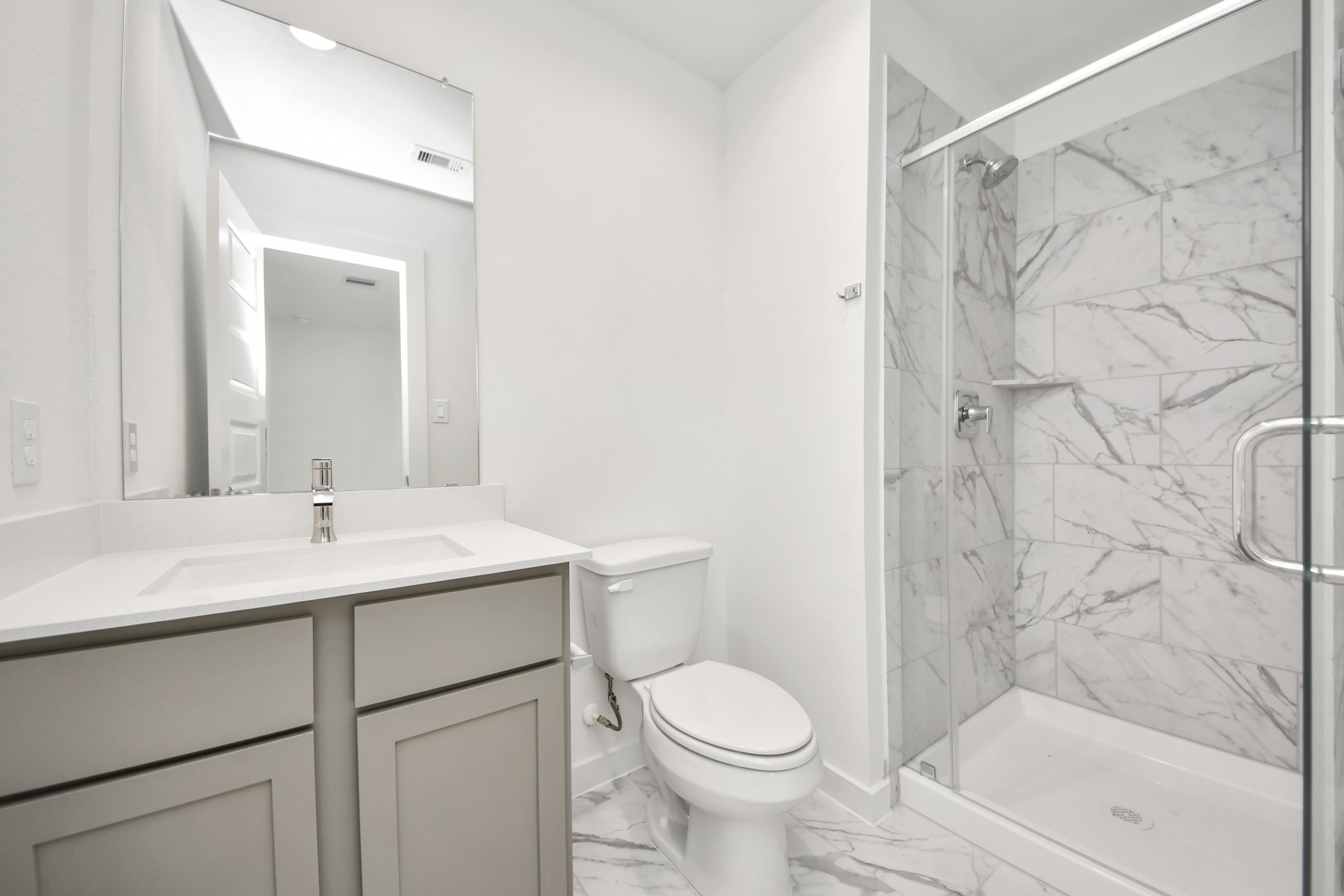 Secondary bath features tile flooring, walk-in shower with tile surround, light stained wood cabinets, beautiful light countertop. Sample photo of completed home with similar floor plan. Actual colors and selections may vary.