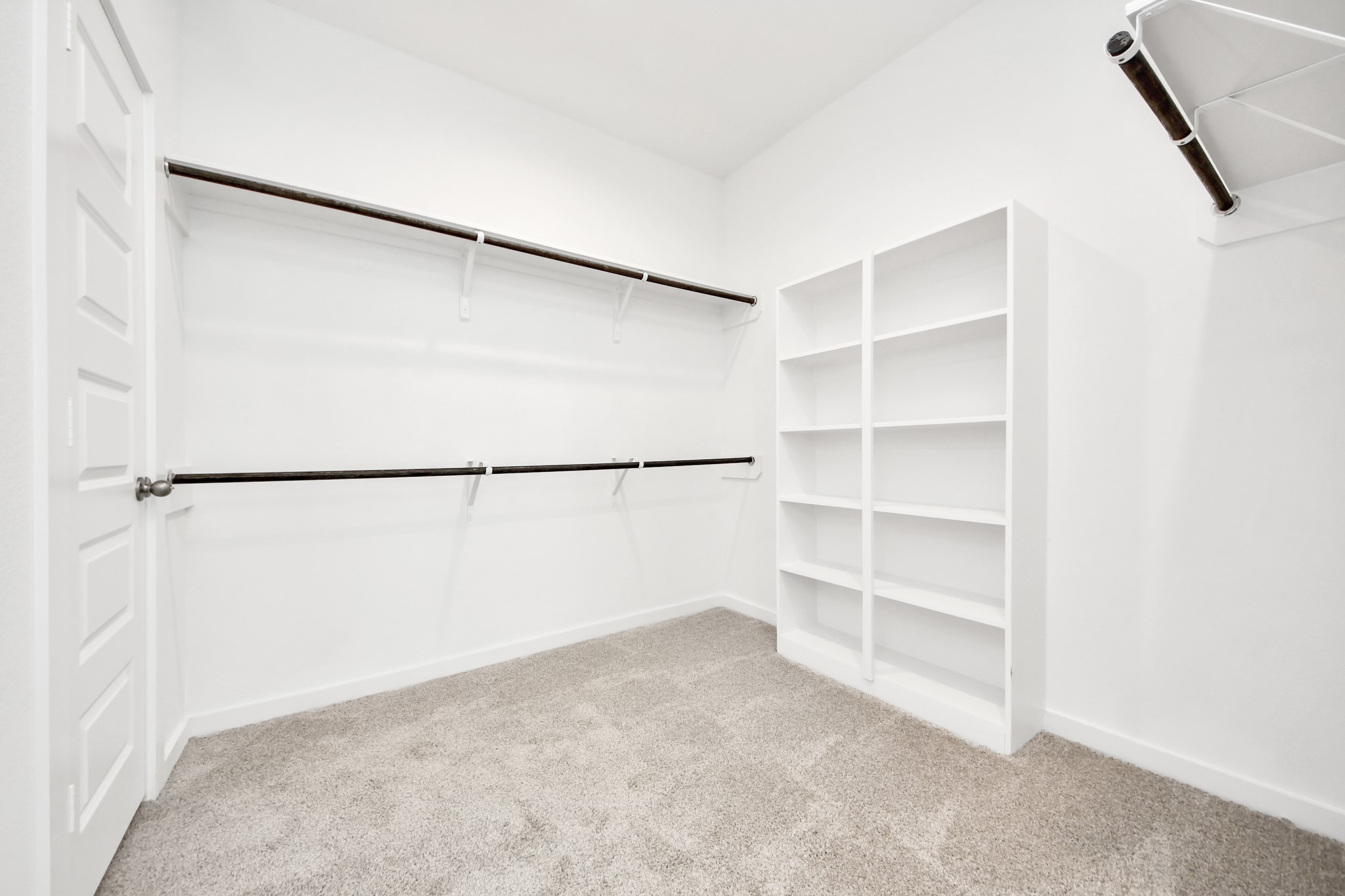 Walk-in closet that epitomizes luxury and practicality. This generously sized space features built-in shelving, offering abundant room for impeccable organization. High ceilings and recessed lighting create a bright and welcoming ambiance. Sample photo of completed home with similar floor plan. Actual colors and selections may vary.