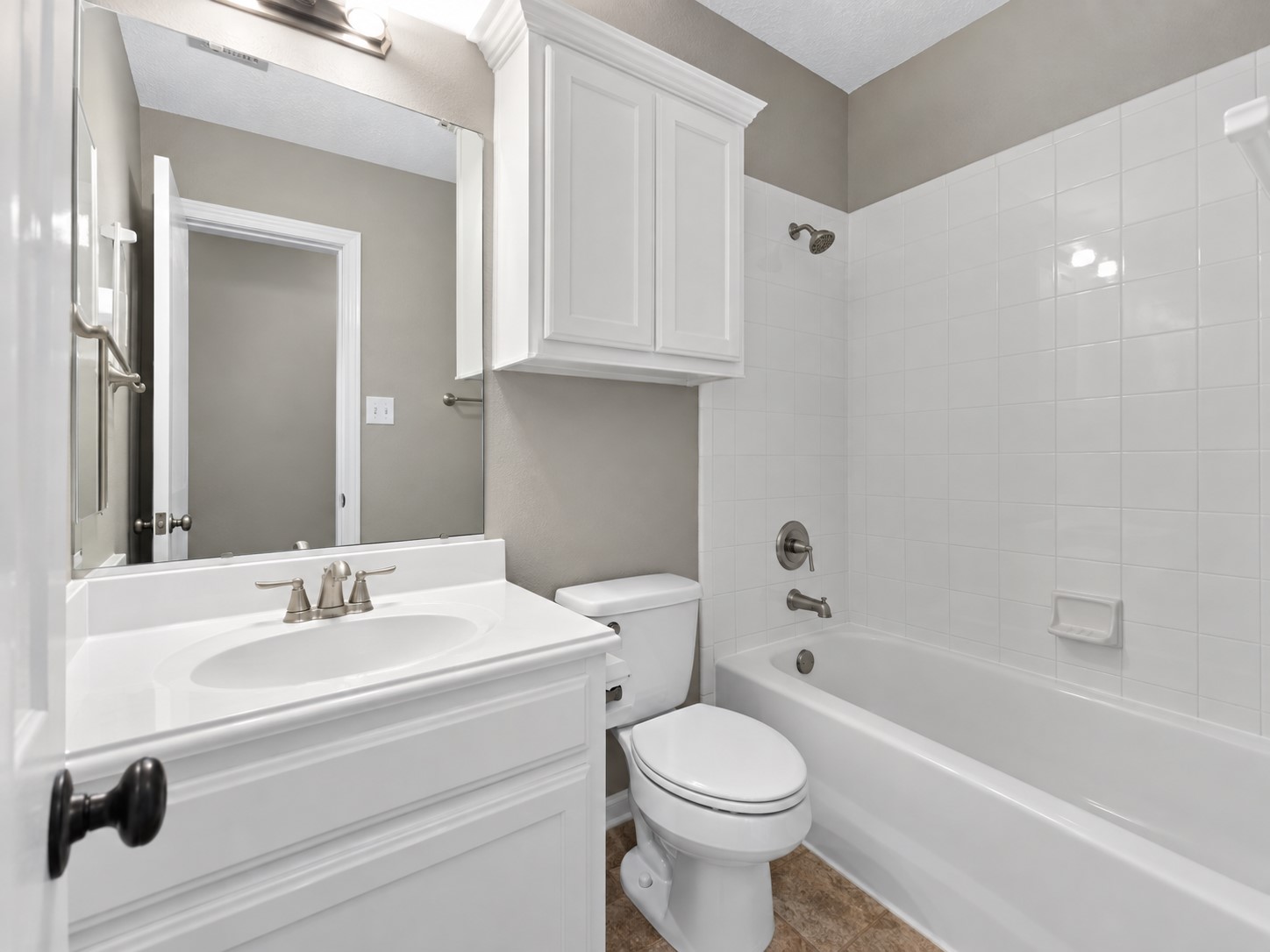 Private ensuite bath with bright white cabinetry and a tub/shower combination.