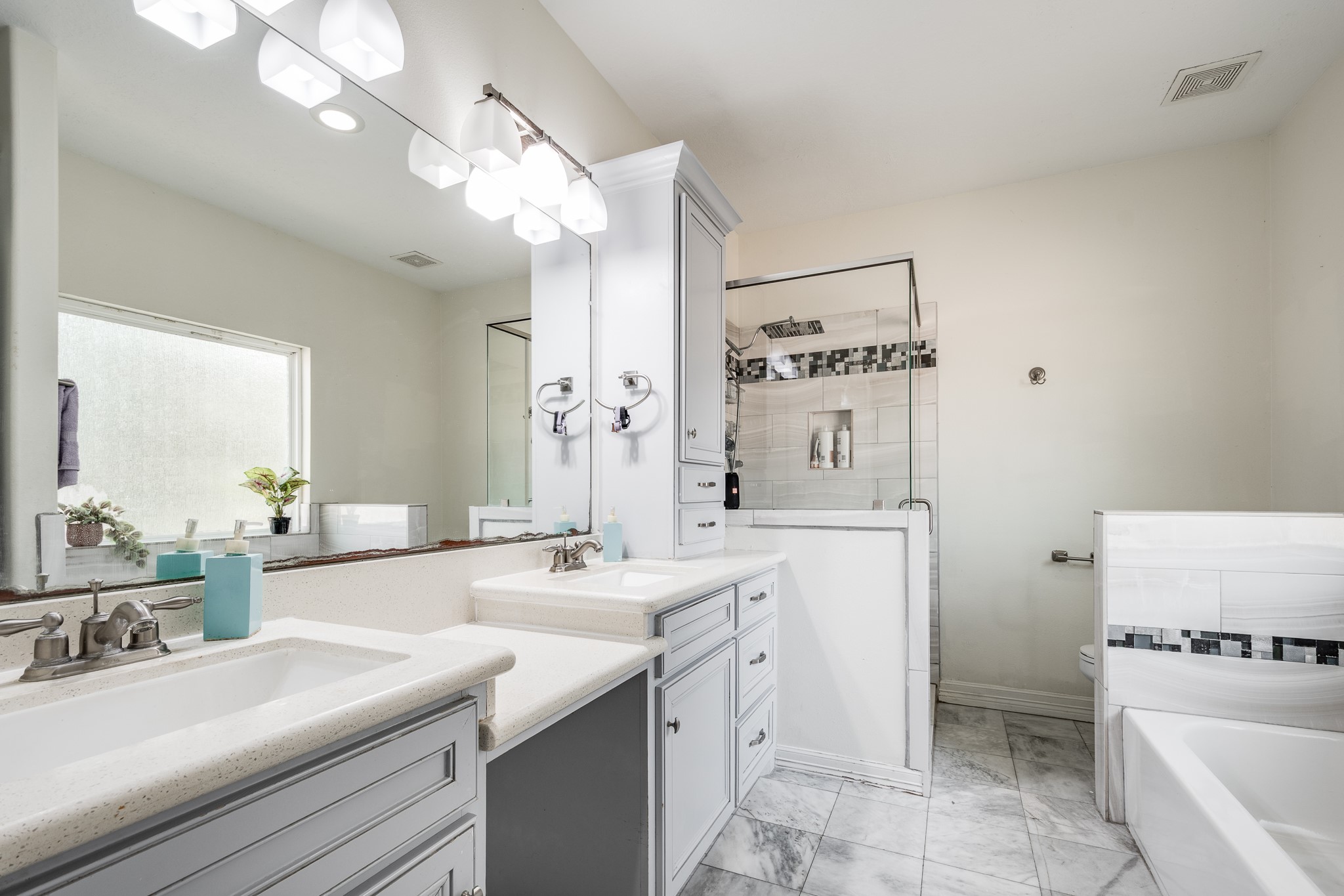 Primary bath with double sinks, a vanity, and separate tub and shower.