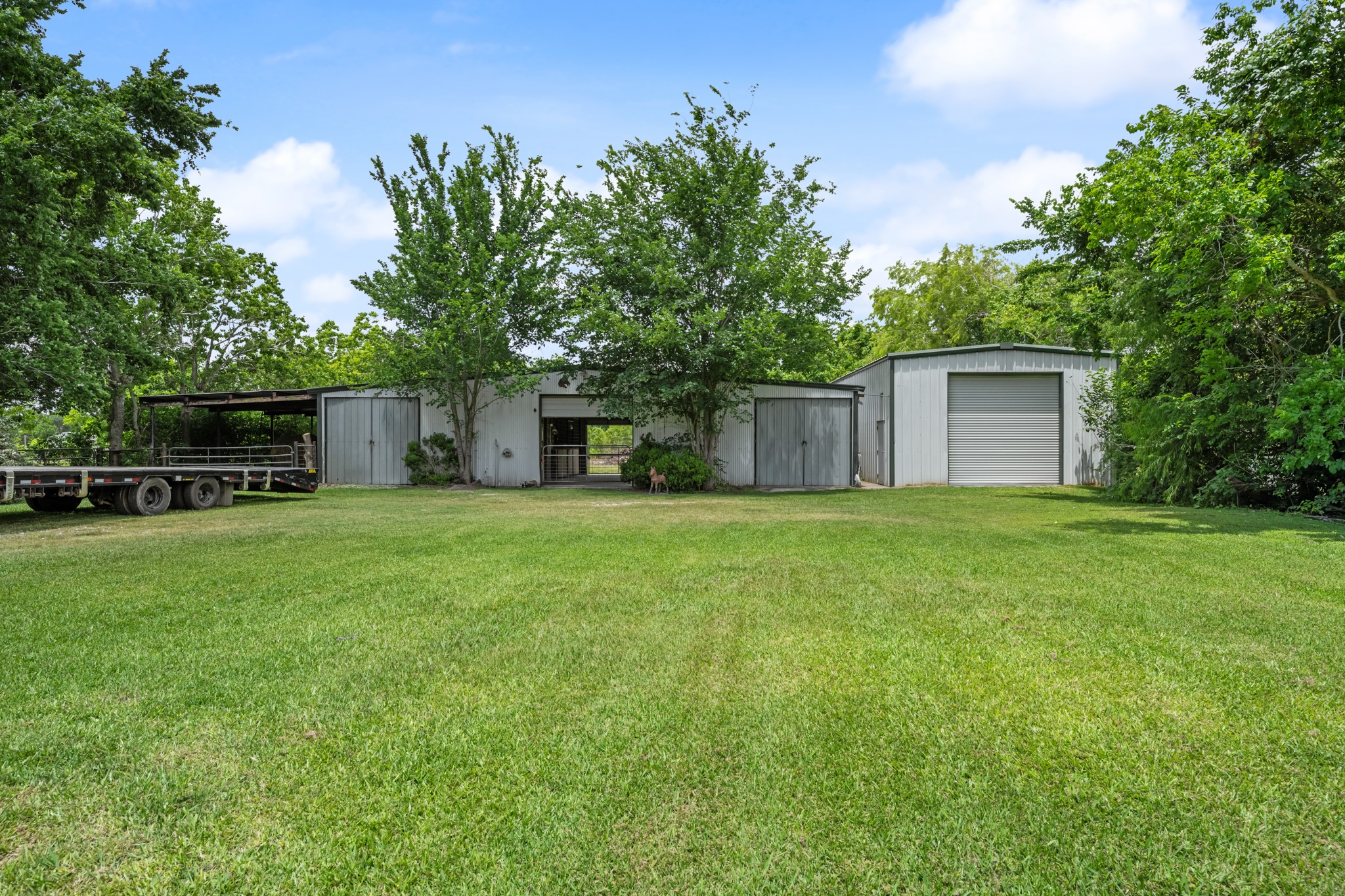 Versatile outbuildings include a horse barn and an insulated workshop, offering ample space for livestock, equipment storage, hobbies, or business use. Surrounded by mature trees and open green space, this setup is ideal for country living and recreational use.