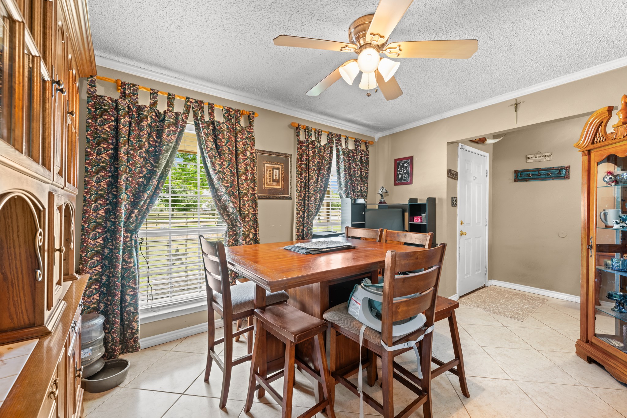 Bright and inviting dining space highlighted by oversized windows, crown molding, and abundant natural light. The open layout offers a comfortable setting for casual meals, entertaining, or gathering with family and friends.
