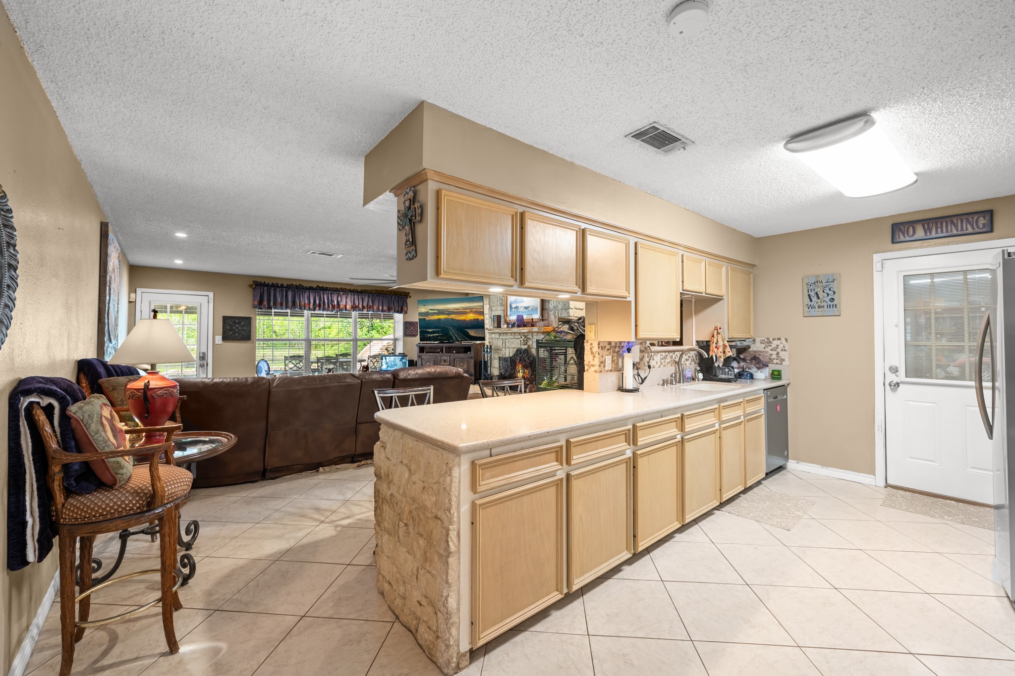 Spacious open-concept kitchen featuring extensive cabinetry, expansive counter space, and seamless flow into the living area. The functional layout, tile flooring, and breakfast bar design make this space ideal for both everyday living and entertaining.