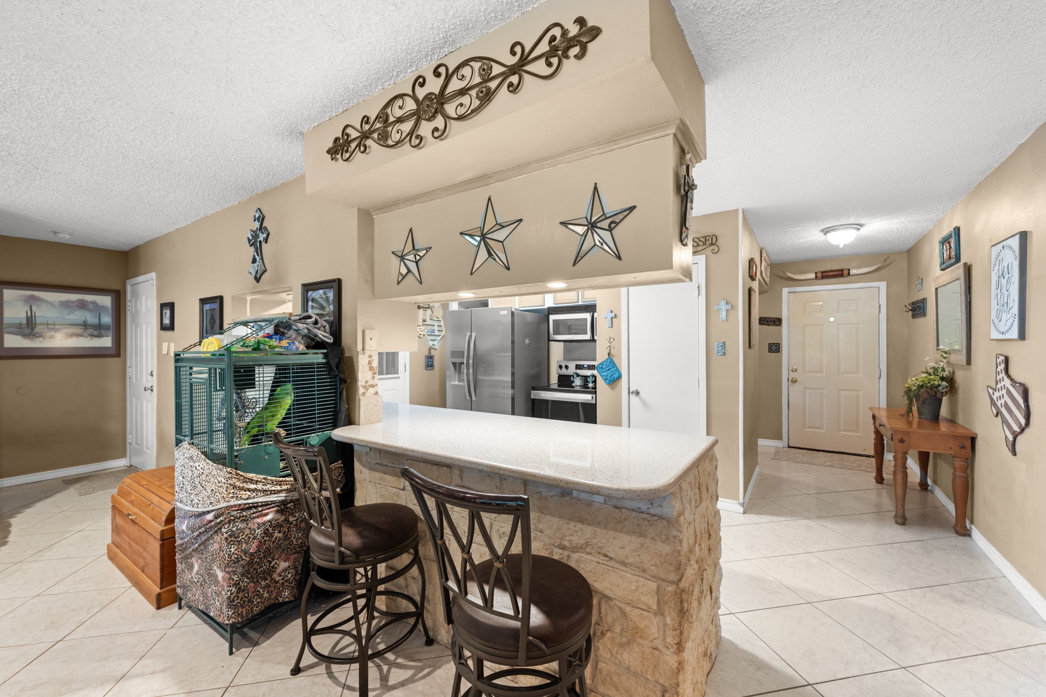Spacious breakfast bar with stone accents and seating overlooks the open-concept living and kitchen areas, creating a welcoming space for casual dining and conversation. Ample counter space and an easy-flow layout enhance both functionality and entertaining potential.