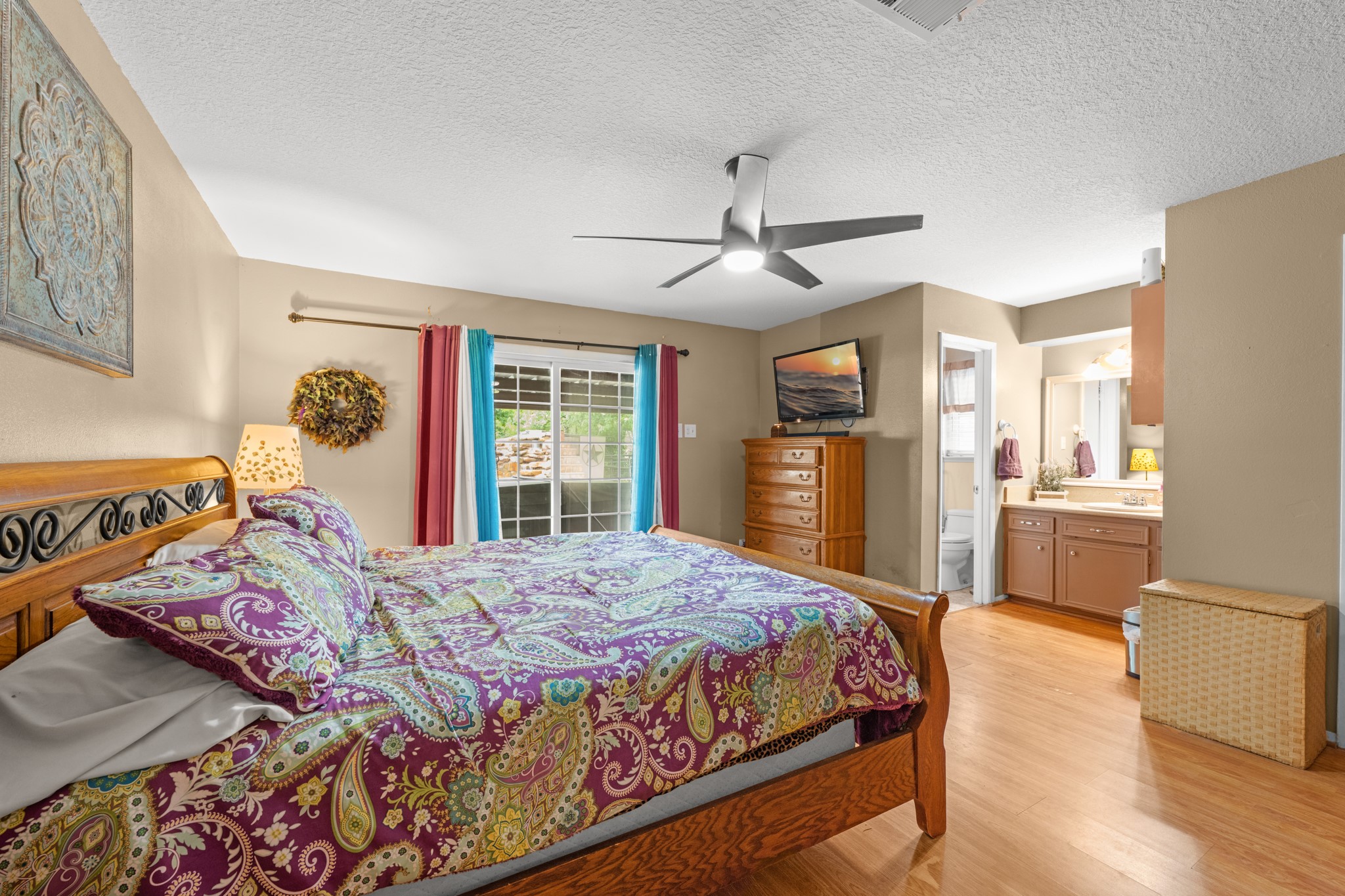 Spacious primary suite featuring wood-look flooring, abundant natural light, and private access to the ensuite bathroom. The generous layout and sliding glass doors create a relaxing retreat with seamless indoor-outdoor connection.