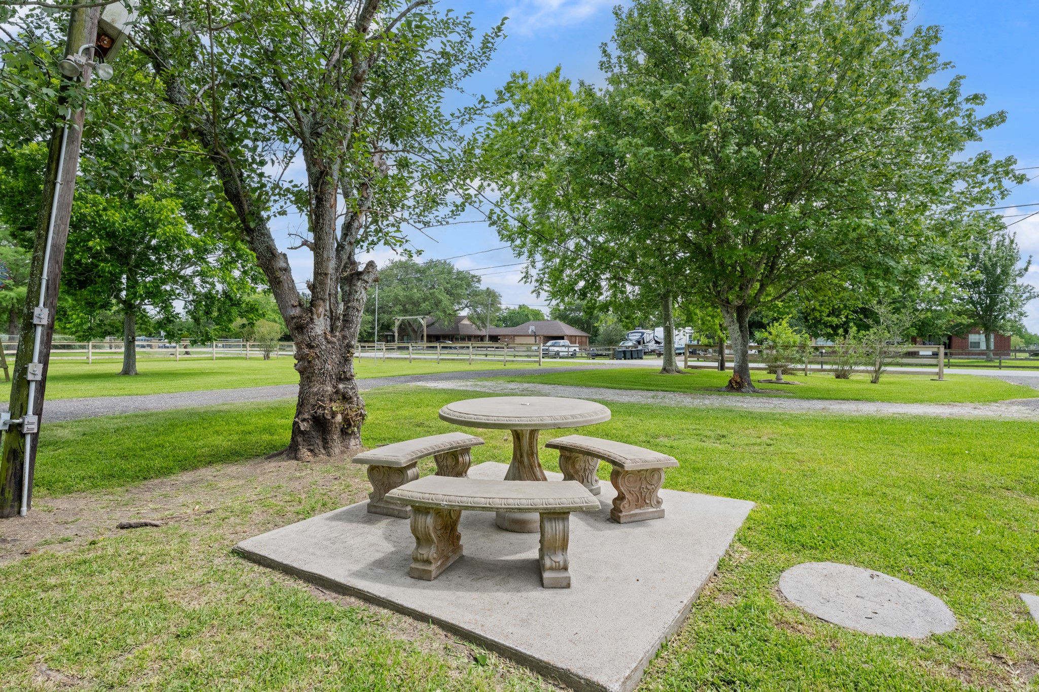 Peaceful outdoor seating area surrounded by mature shade trees and expansive green space, offering the perfect setting to relax and enjoy the propertys tranquil surroundings. The spacious yard provides plenty of room for outdoor activities, gardening, or entertaining.