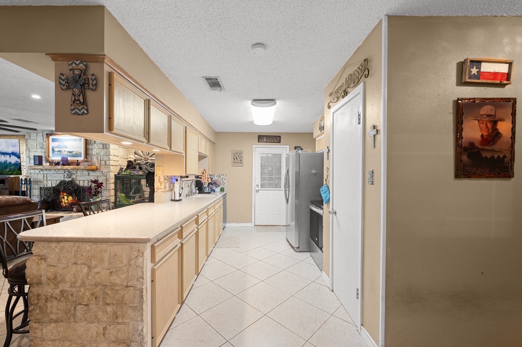 Bright and functional kitchen featuring abundant cabinetry, expansive countertops, and a convenient breakfast bar with stone accents. The open layout overlooks the living area, creating an ideal setup for entertaining and everyday gatherings.