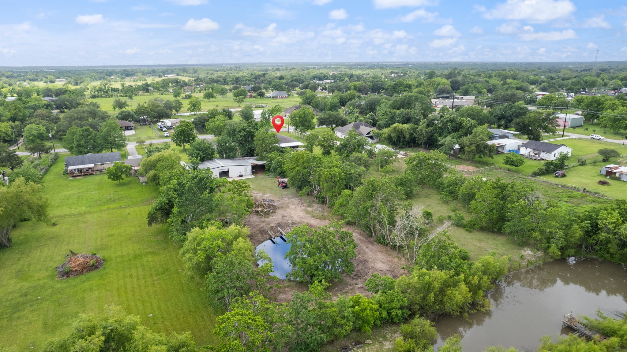 Sweeping aerial perspective highlighting the propertys expansive grounds, mature trees, open pasture areas, and additional land features. Ideal for those seeking extra space, privacy, and room for livestock, recreation, or future projects.