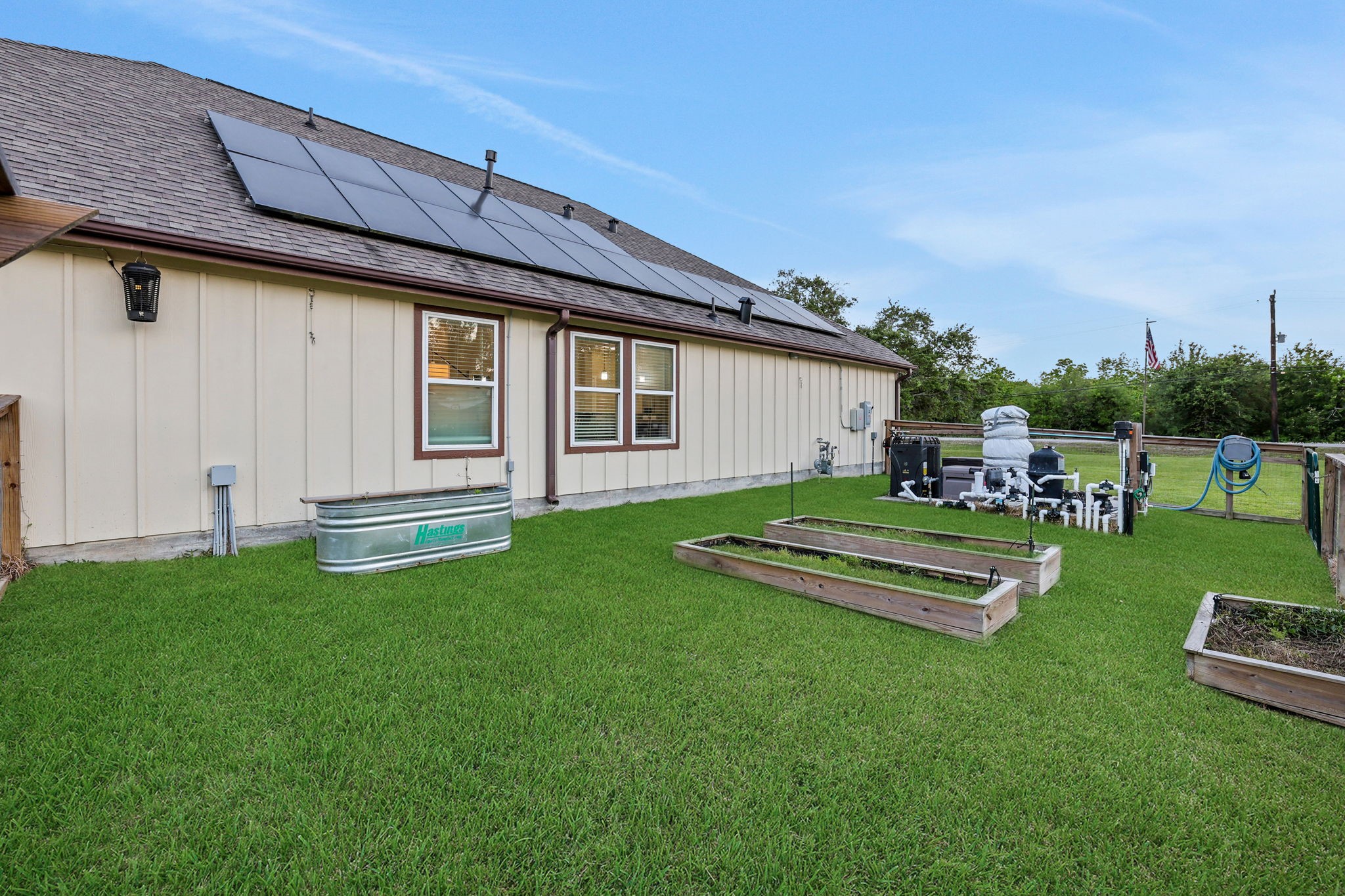 Energy-efficient home with solar panels, a spacious backyard, and raised garden beds for sustainable living.