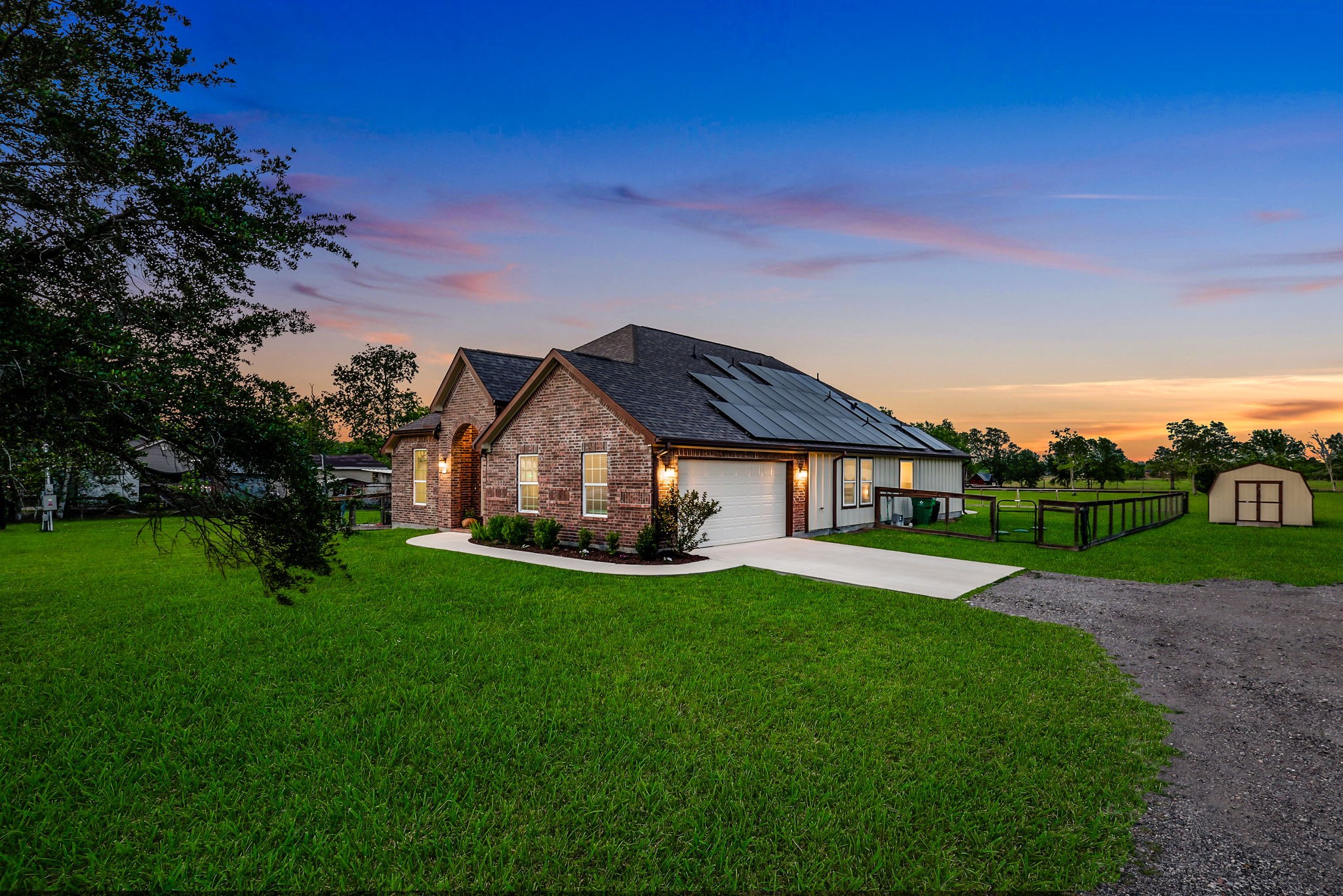 Discover a serene retreat with an expansive driveway perfect for hosting guests, nestled in a picturesque setting at sunset.