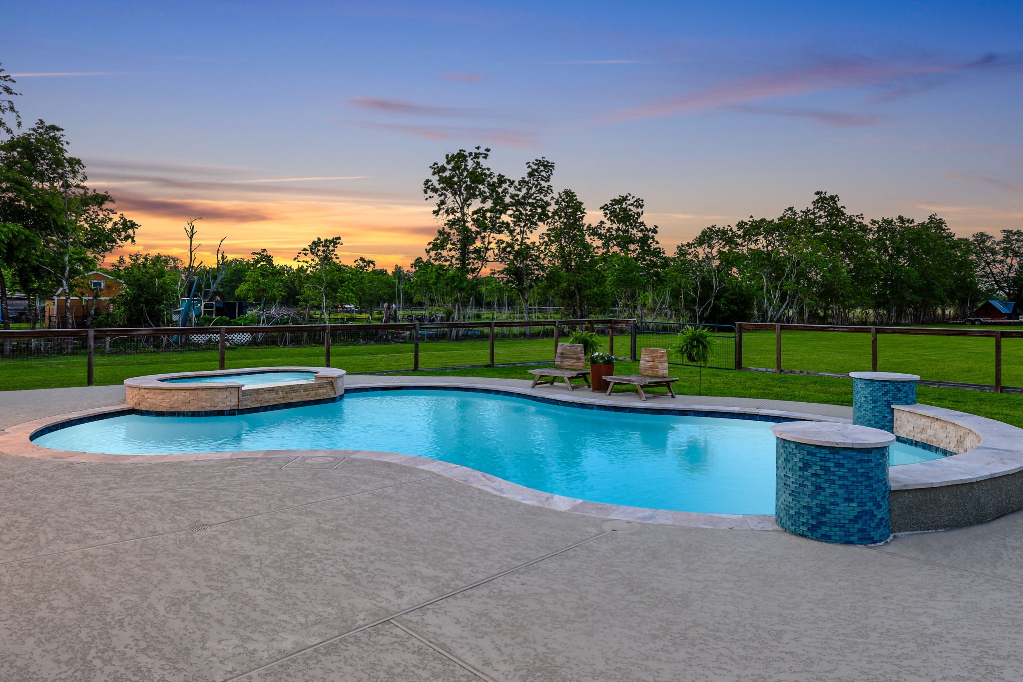 Enjoy serene sunsets by the sparkling pool and spa, surrounded by lush greenery and expansive views, perfect for relaxation and outdoor entertaining.