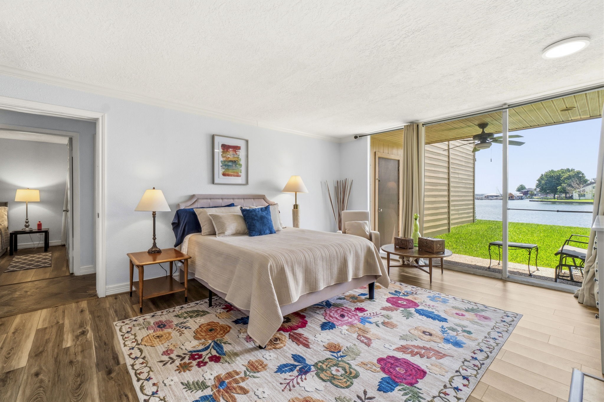 Waterfront Primary Retreat Spacious primary bedroom featuring a cozy fireplace, wall-mounted TV, and breathtaking lake views through expansive sliding glass doors.