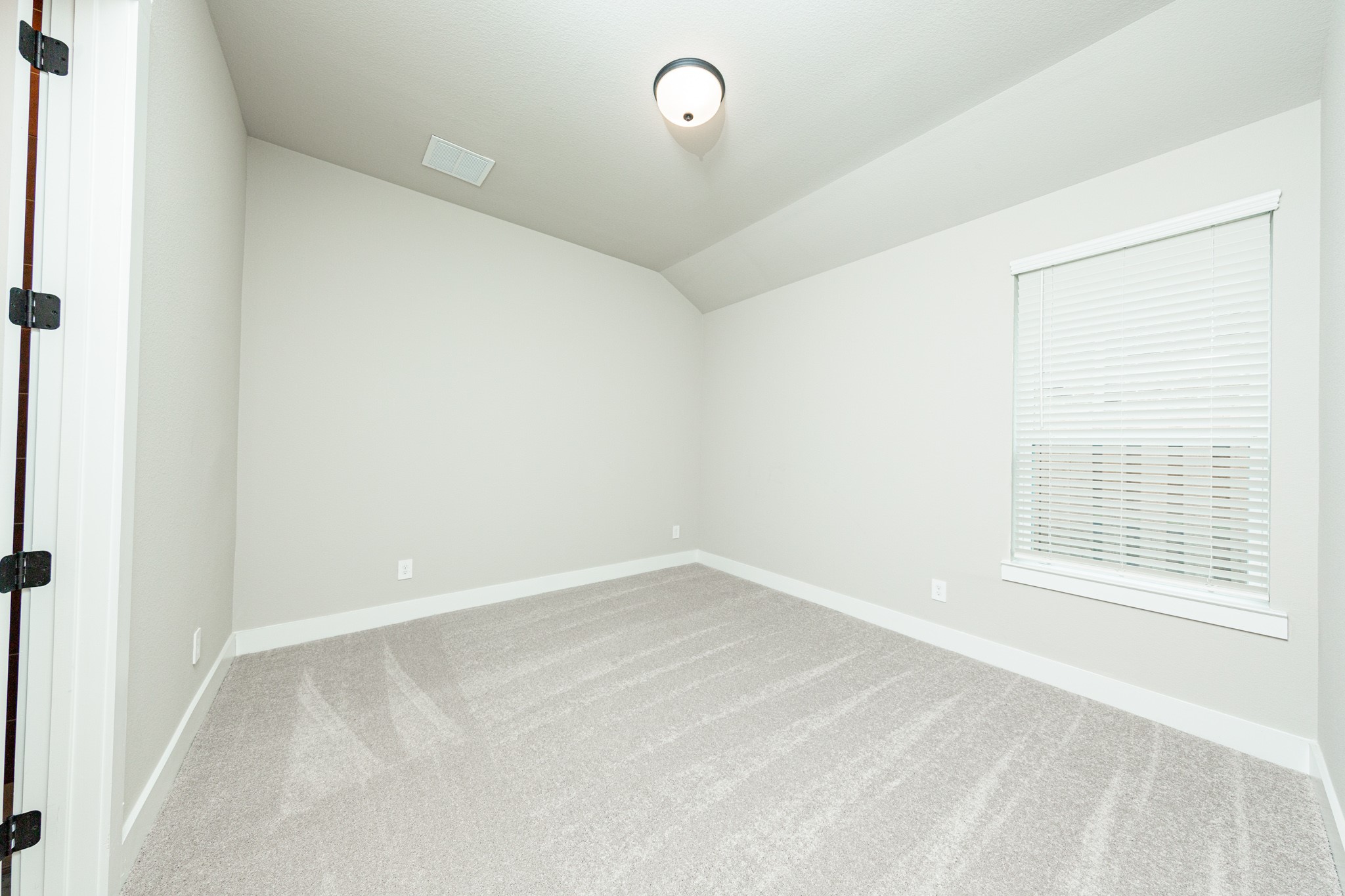 This secondary bedroom features a sloped ceiling, plush carpet flooring, a large window, a walk-in closet, and an ensuite secondary bathroom.
