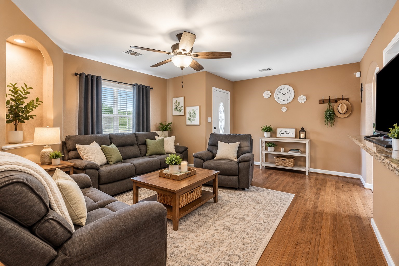 Open and inviting, this living room features durable wood-look flooring, a ceiling fan for year-round comfort, and a cozy archway that adds character.