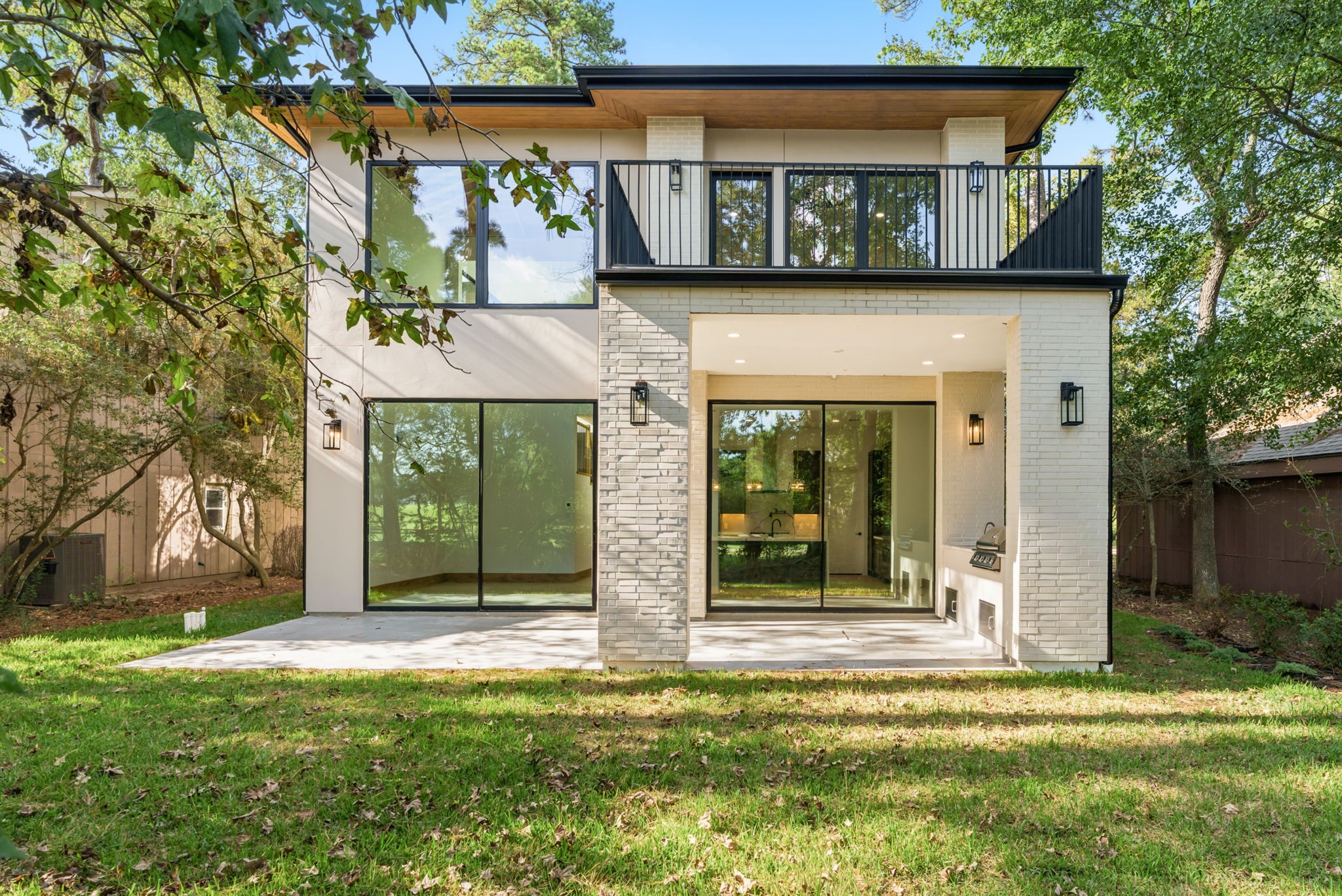 Stunning rear exterior featuring a covered patio with a fully equipped outdoor kitchen, built-in grill, and prep sink.