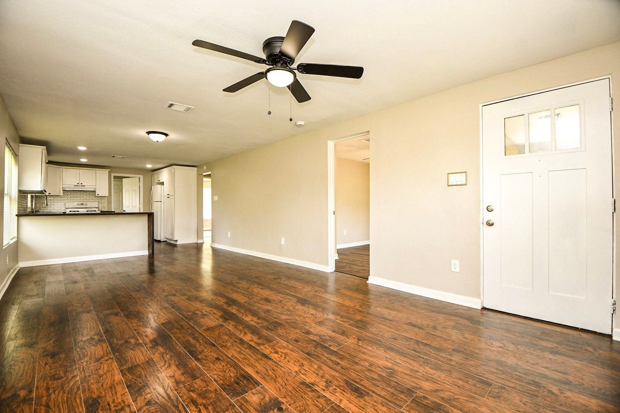 Living area with a ceiling fan and an open layout leading straight to the kitchen.